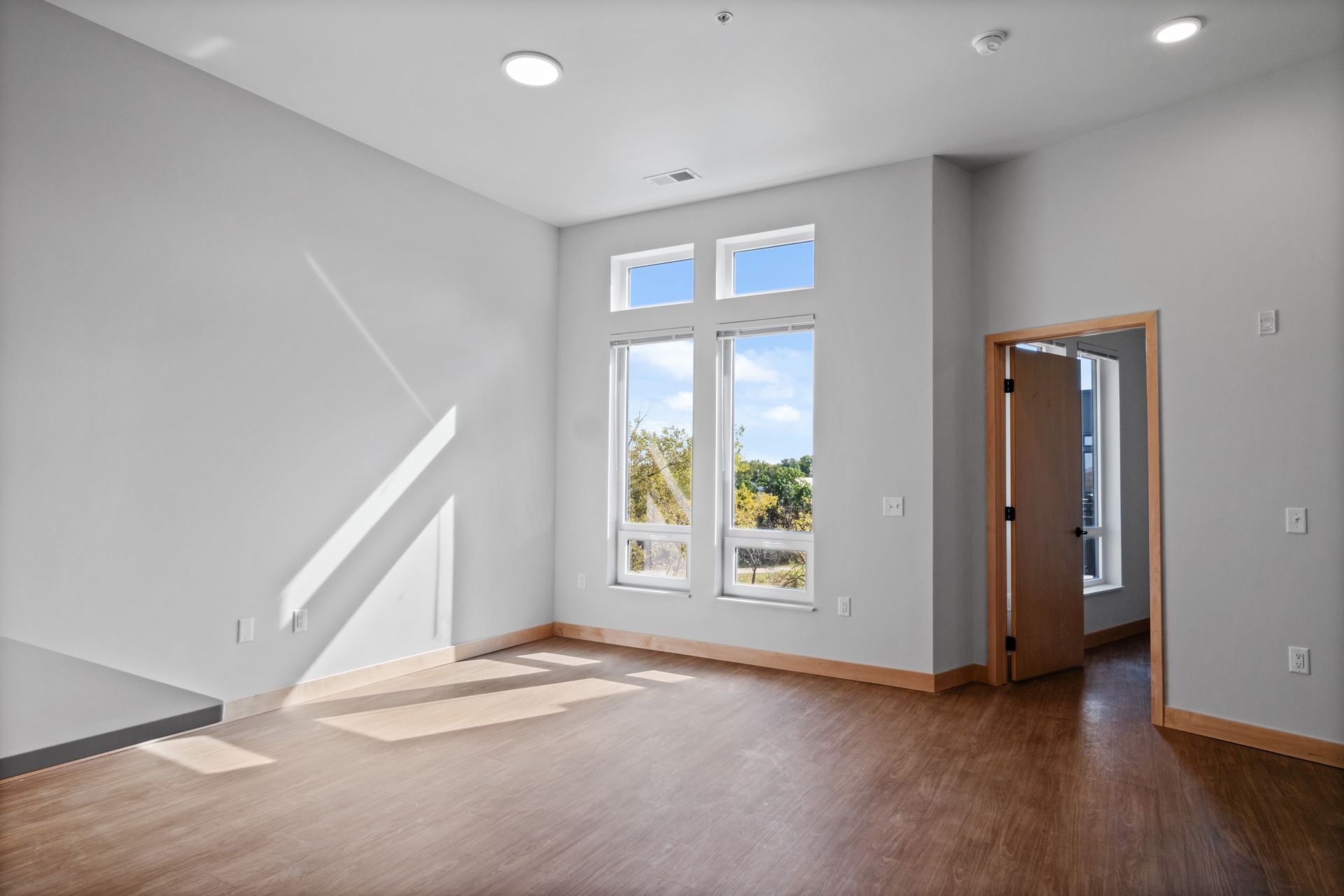An empty living room with hardwood floors and white walls.