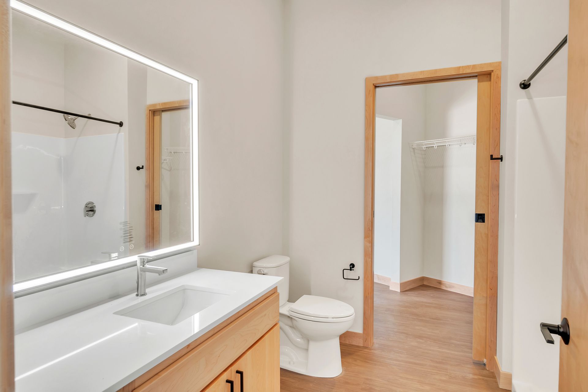 A bathroom with a toilet , sink , mirror and walk in closet.