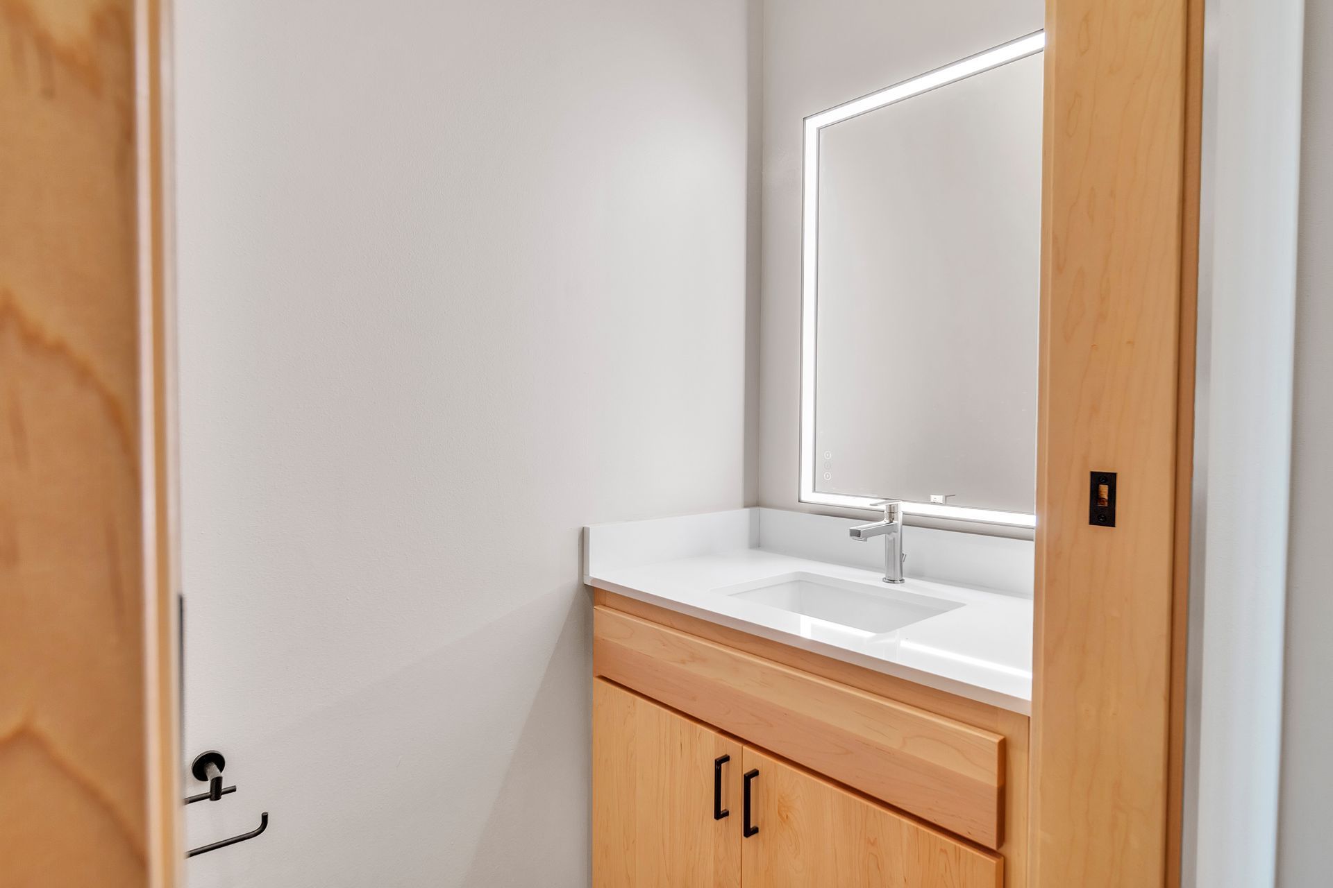 A bathroom with a sink , mirror and wooden cabinets.