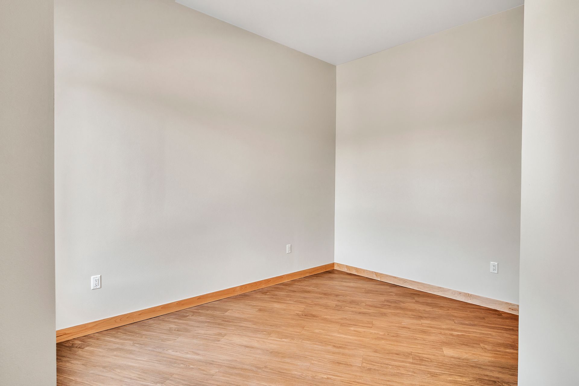 An empty room with hardwood floors and white walls.