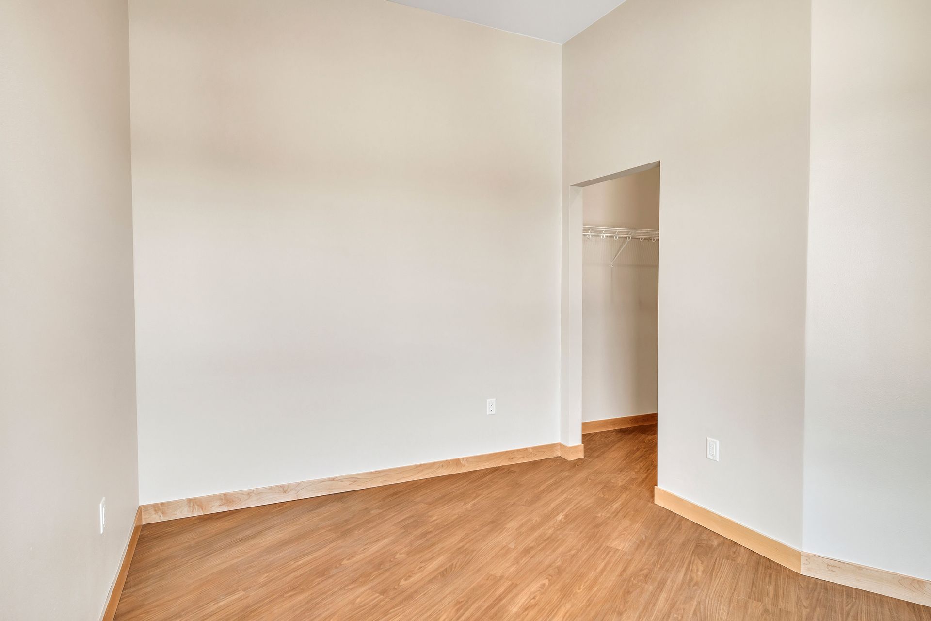 An empty room with hardwood floors and white walls.