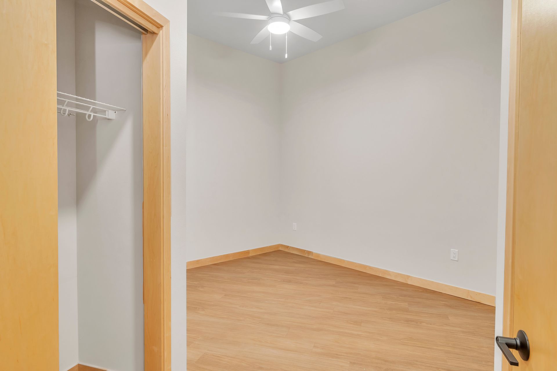 An empty bedroom with a ceiling fan and a closet.