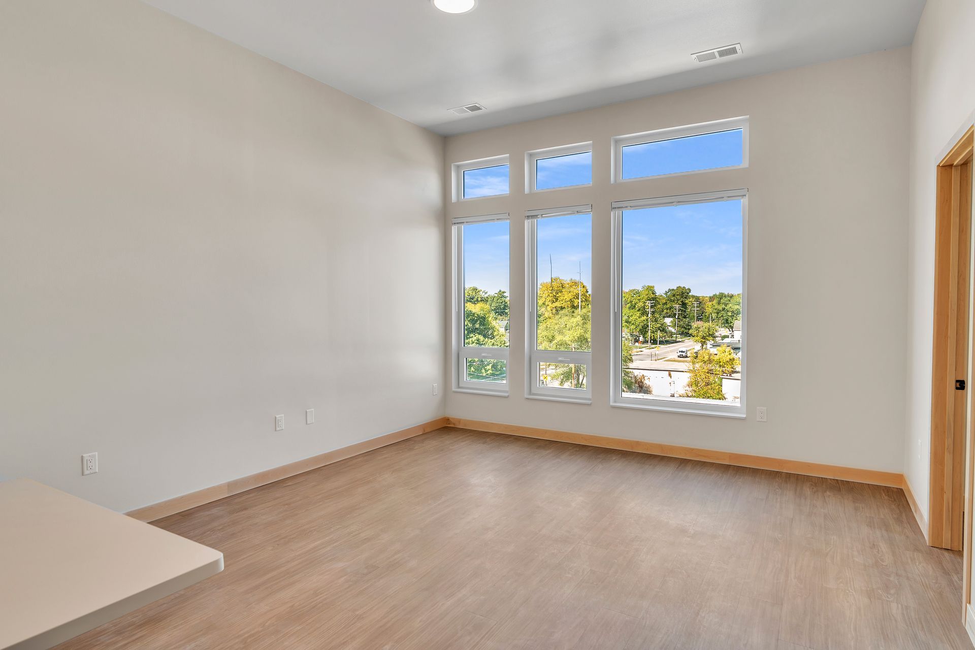 An empty room with a lot of windows and a wooden floor.