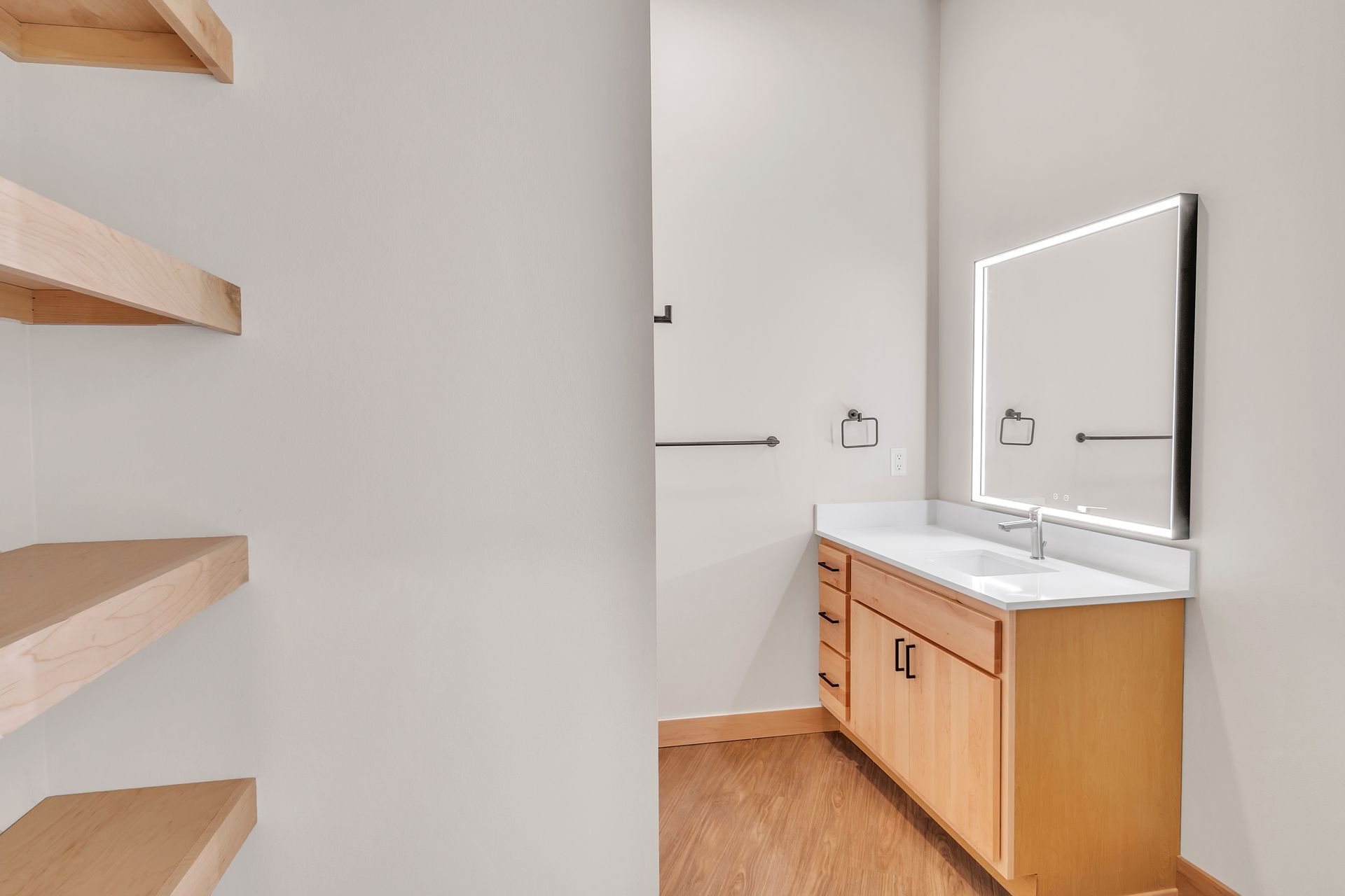 A bathroom with a sink , mirror and shelves.