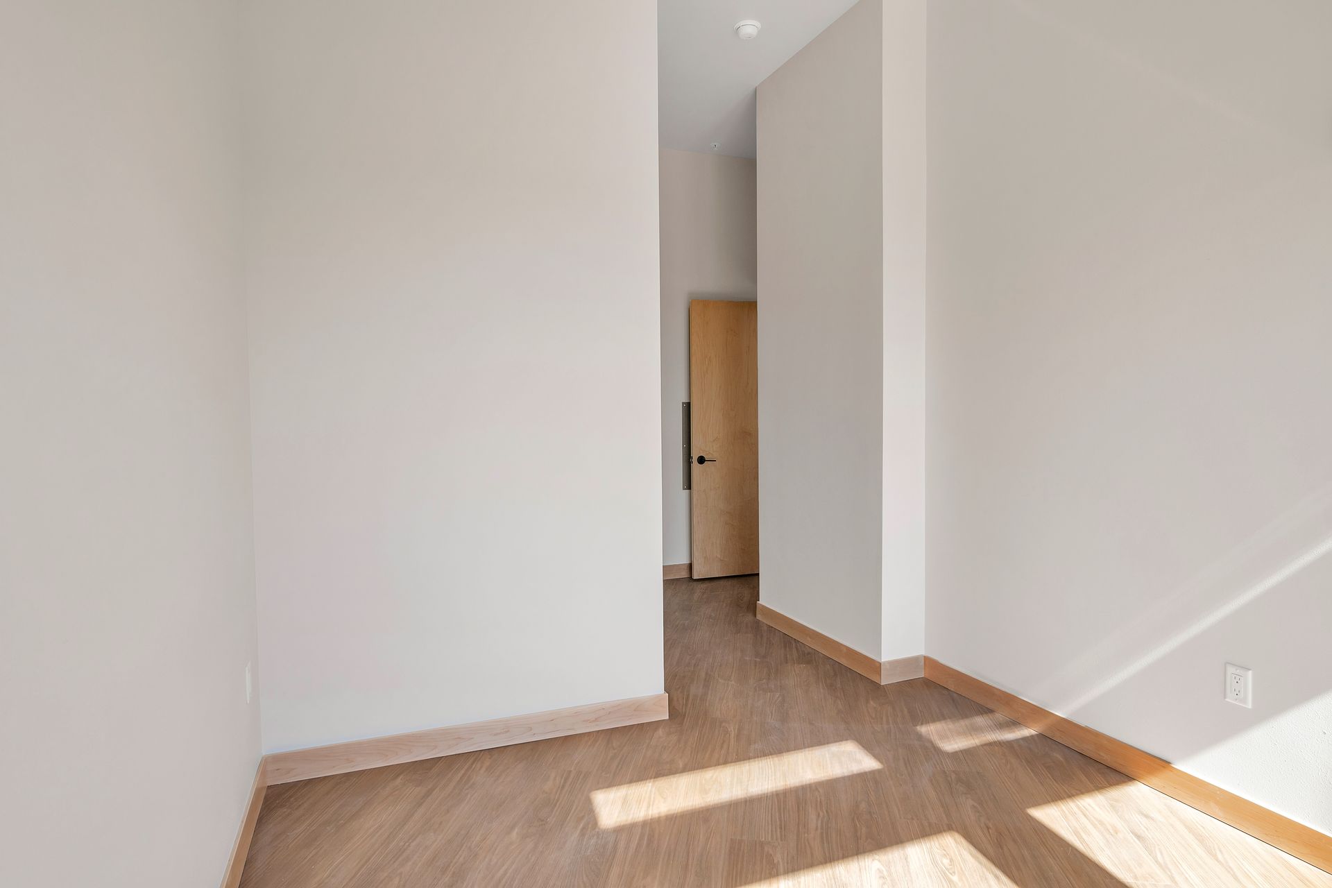 An empty room with a wooden floor and white walls.