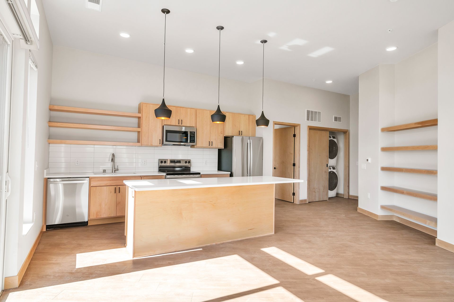 An empty kitchen with wooden cabinets , stainless steel appliances , and a large island.