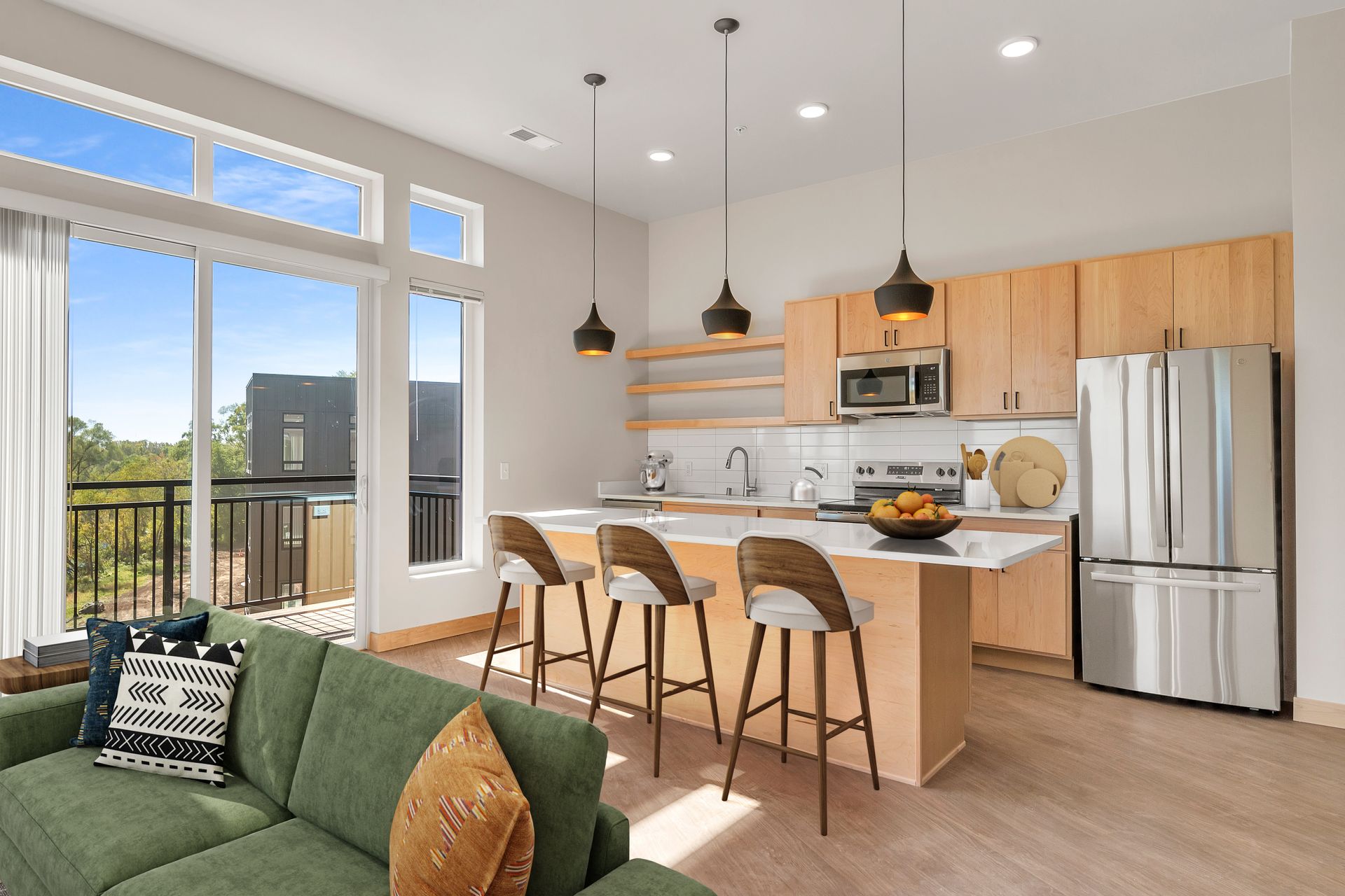 A living room with a green couch and a kitchen with stainless steel appliances.