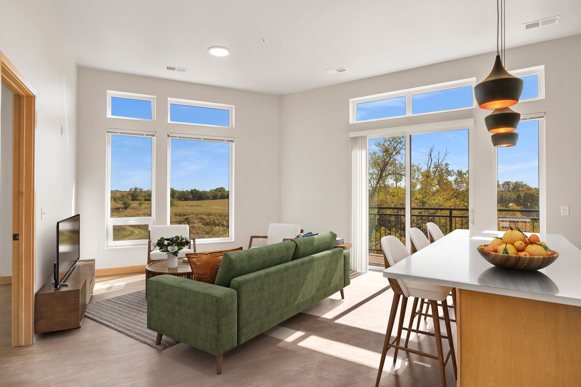 A living room with a green couch , television , and sliding glass doors.