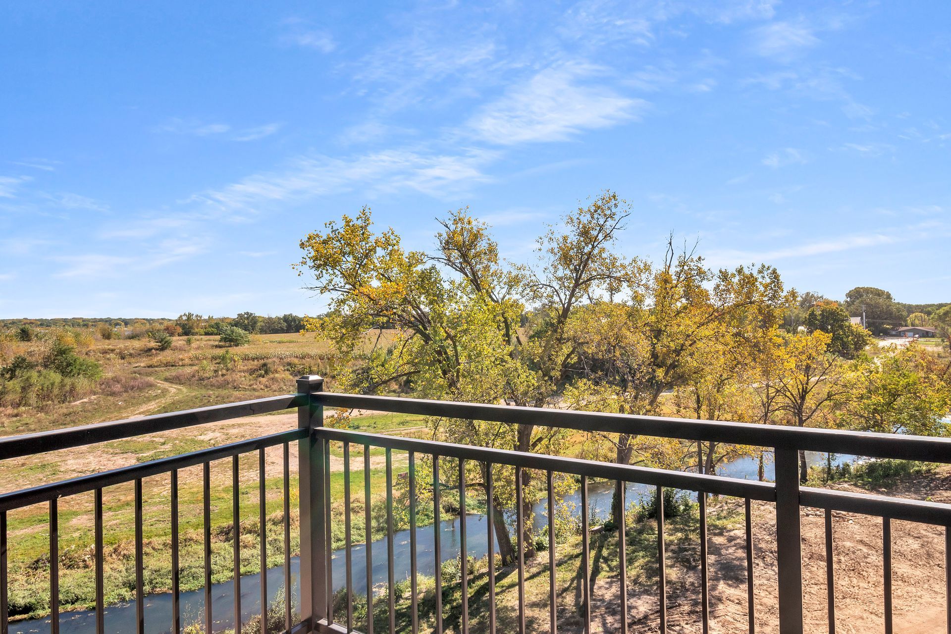 A balcony with a view of a river and trees.