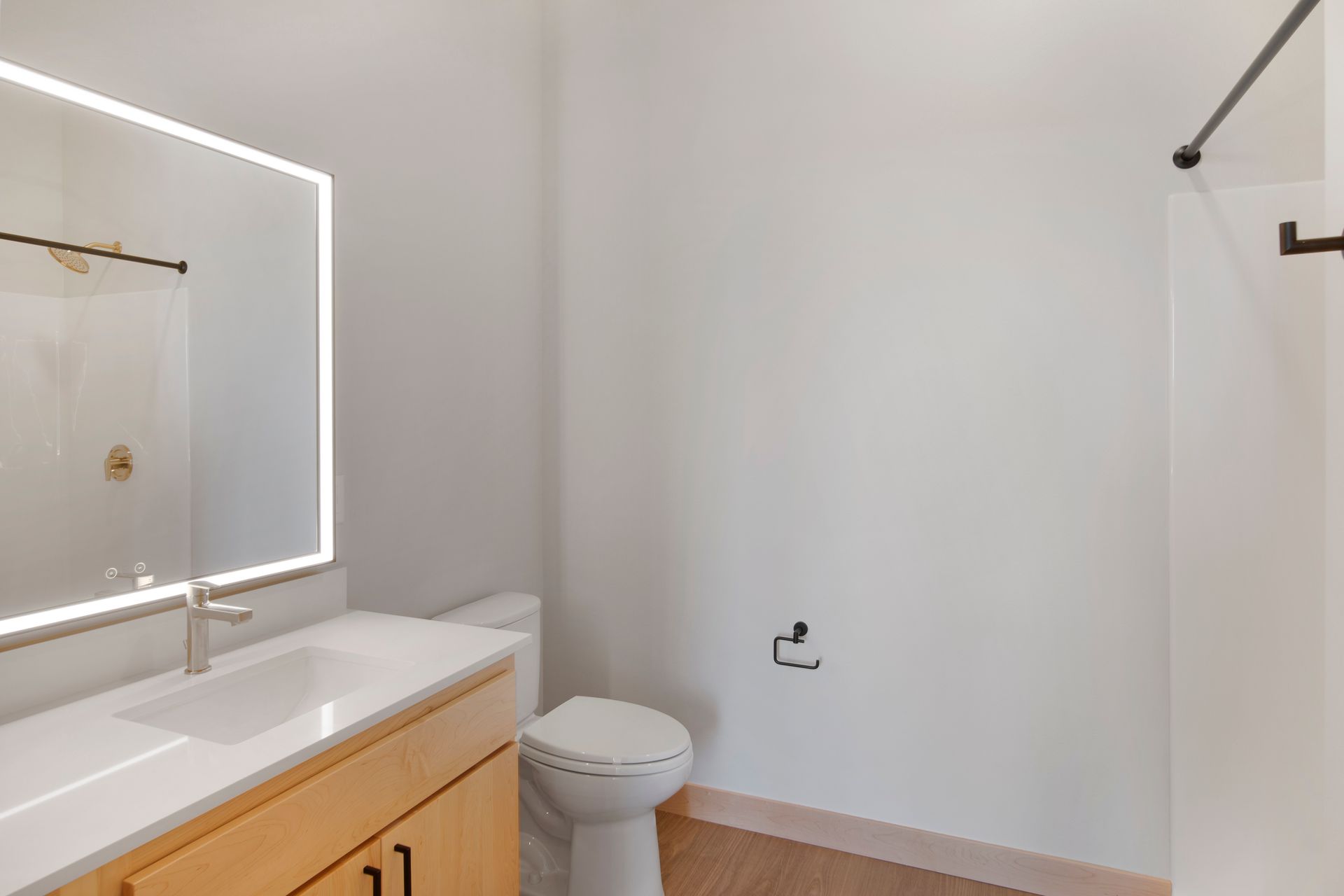 A bathroom with a toilet , sink , led mirror and shower.
