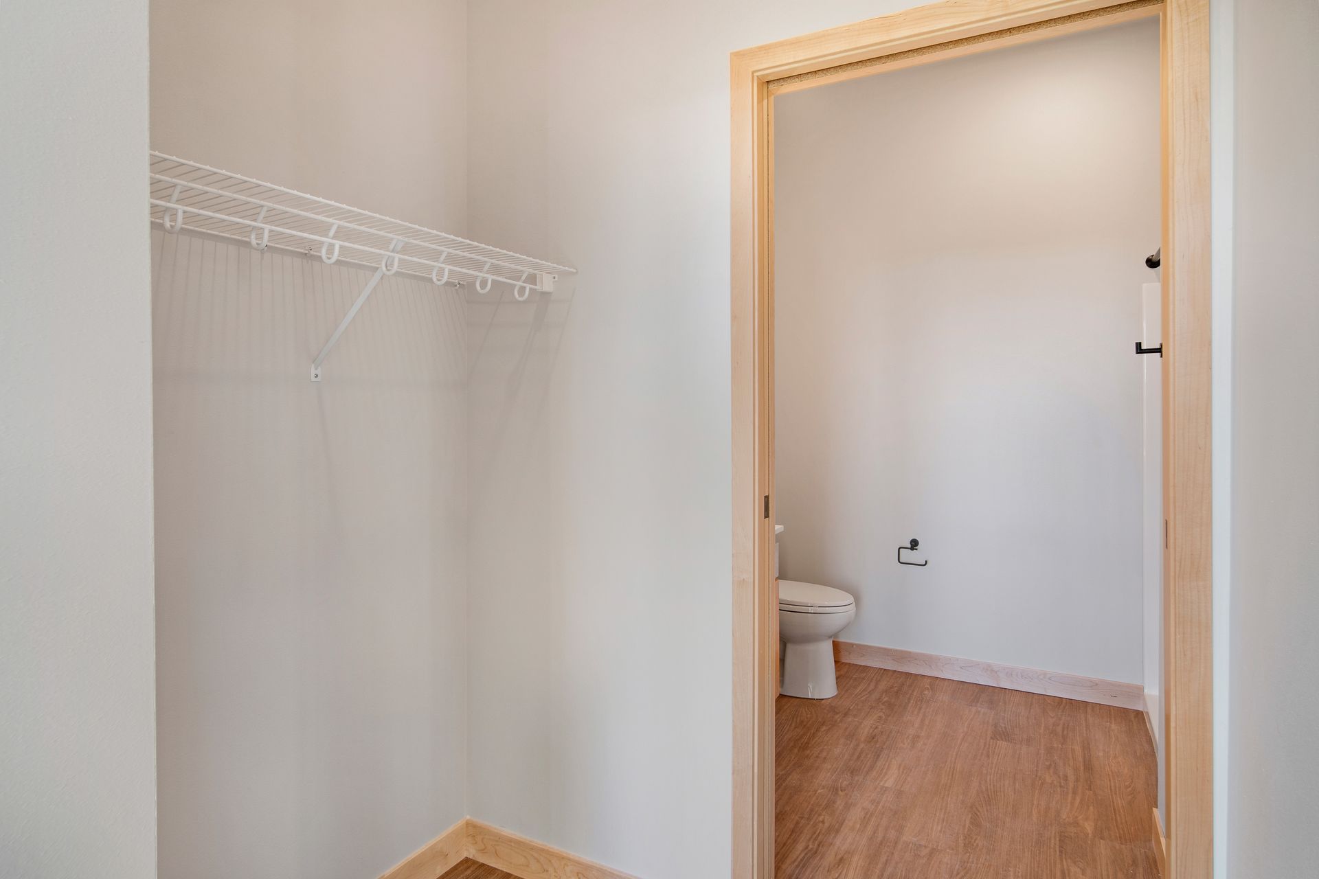 A walk in closet with a toilet and a closet.