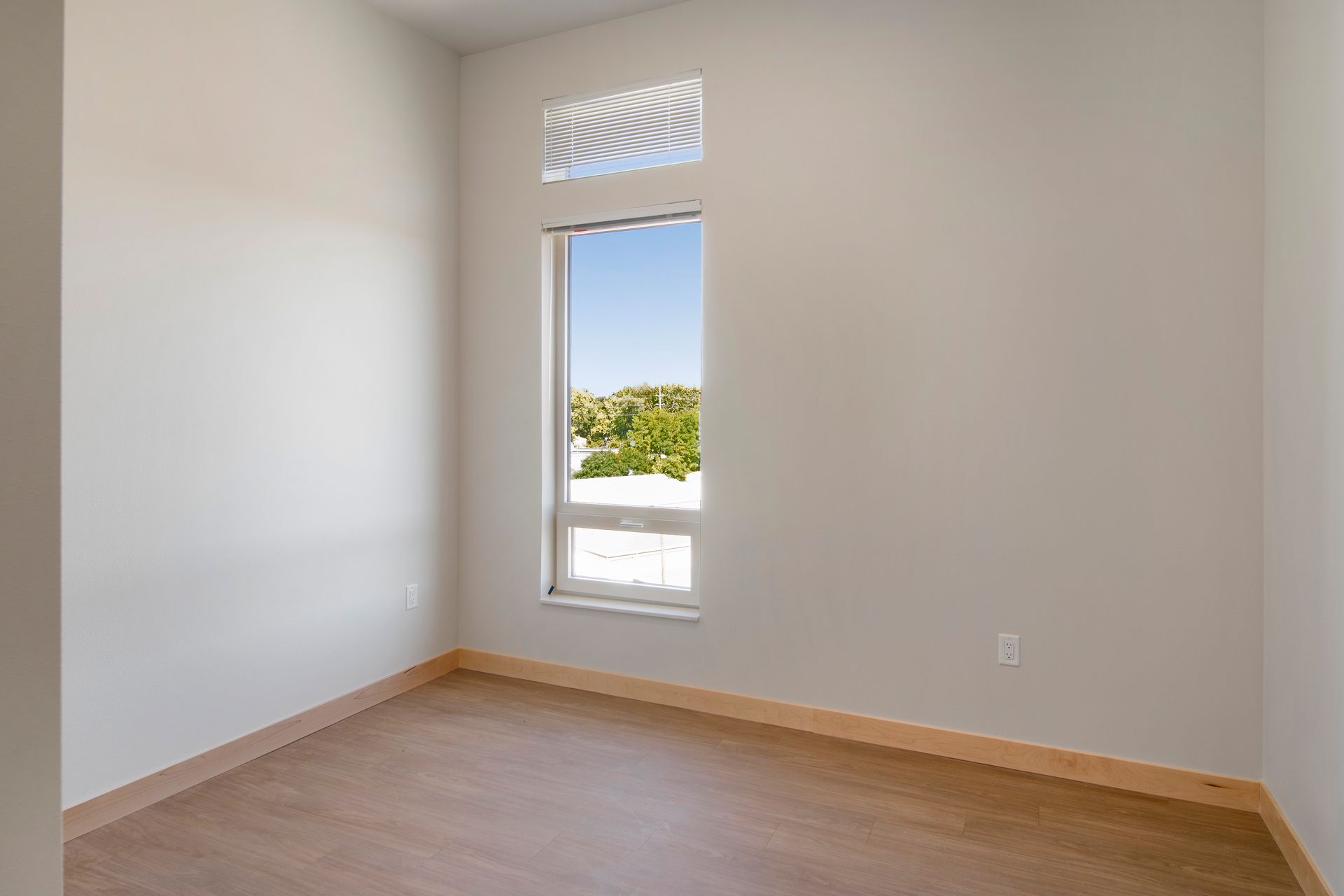 An empty room with a window and a wooden floor.