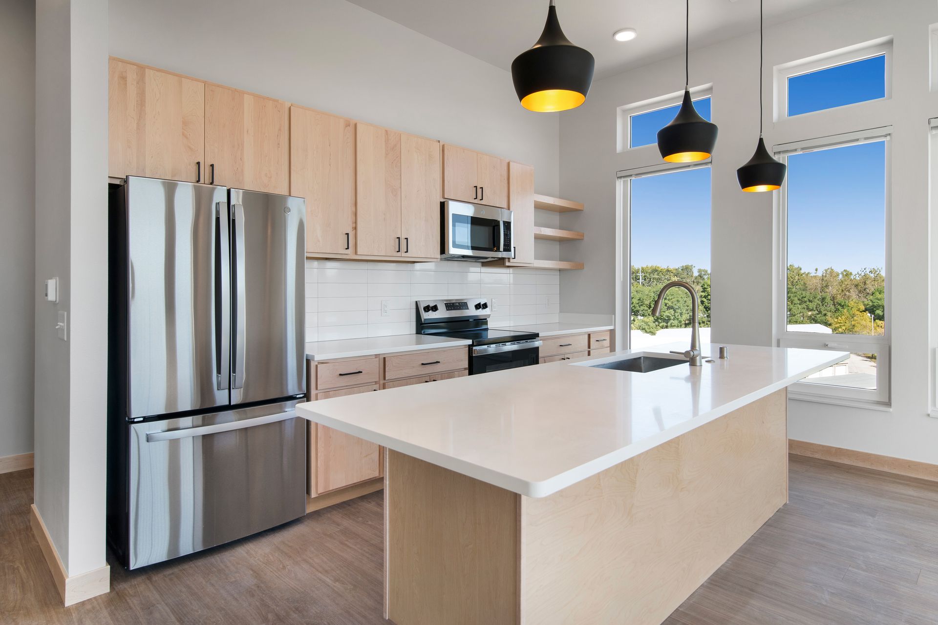 A kitchen with stainless steel appliances , wooden cabinets and a large island.