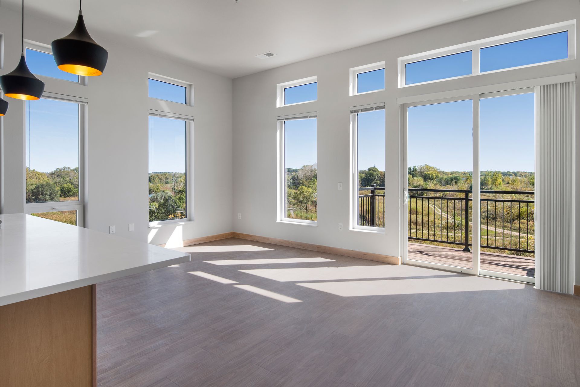 An empty living room with lots of windows and a balcony.
