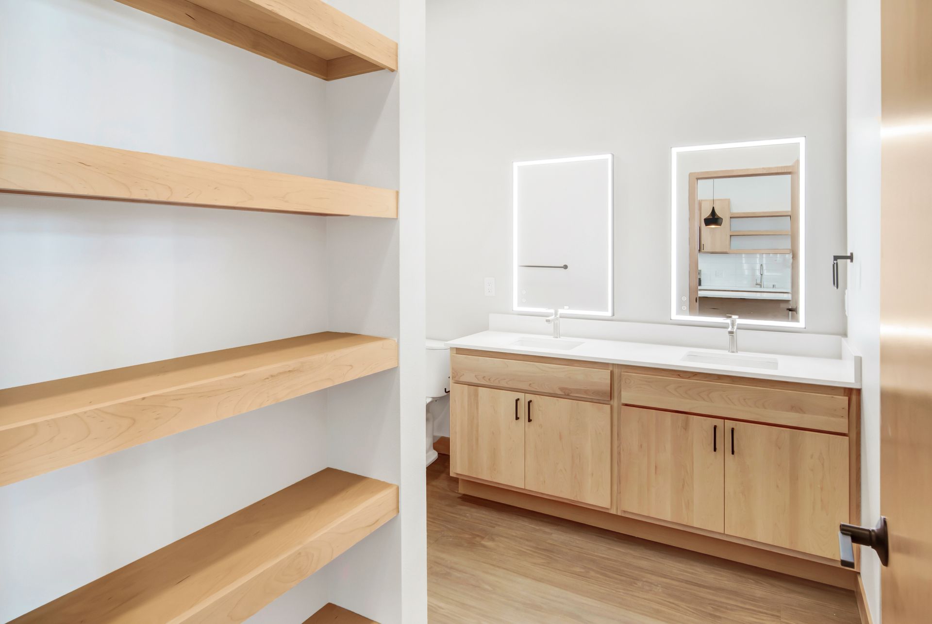 A bathroom with two sinks , two mirrors , and wooden cabinets.
