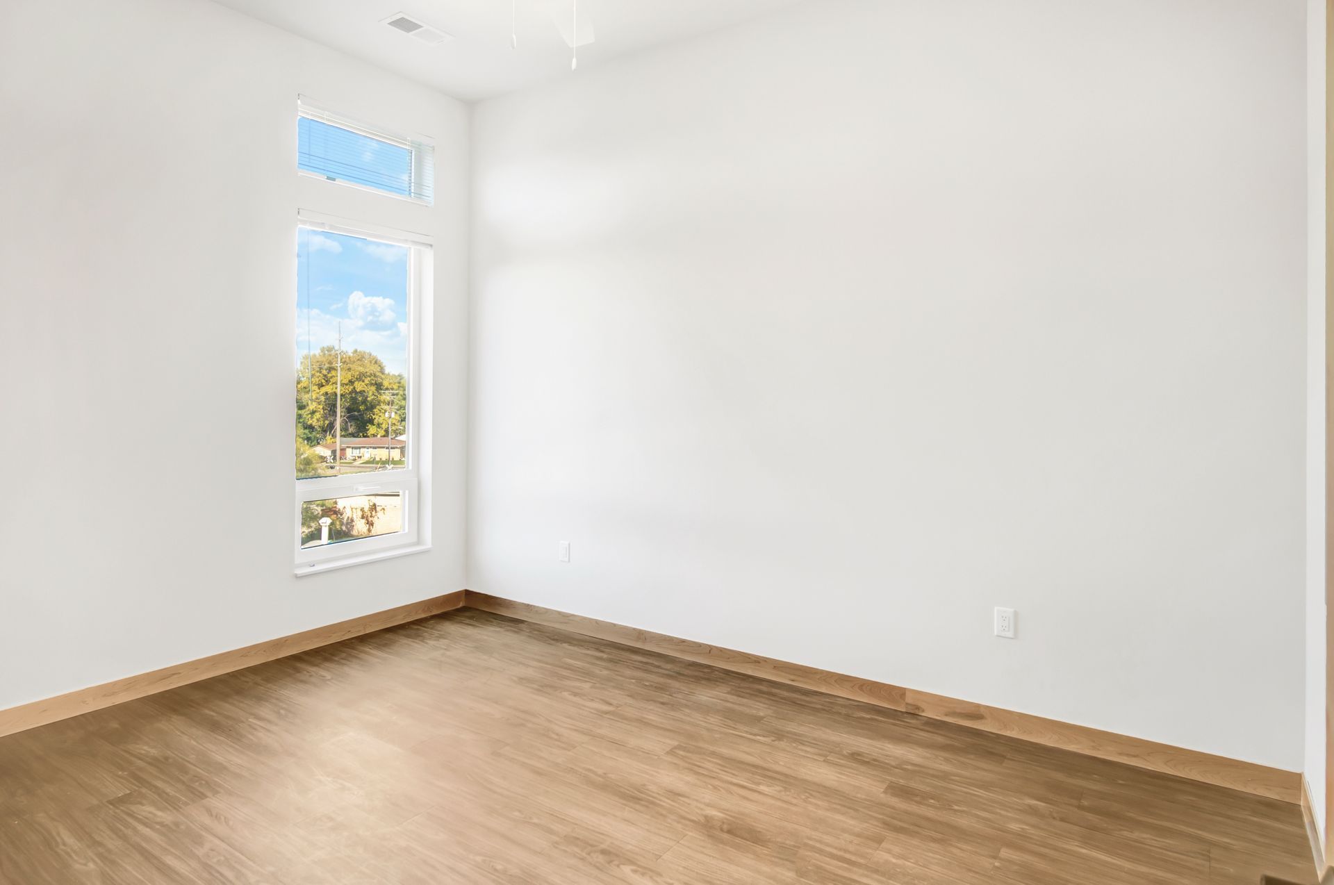 An empty room with hardwood floors and a window.