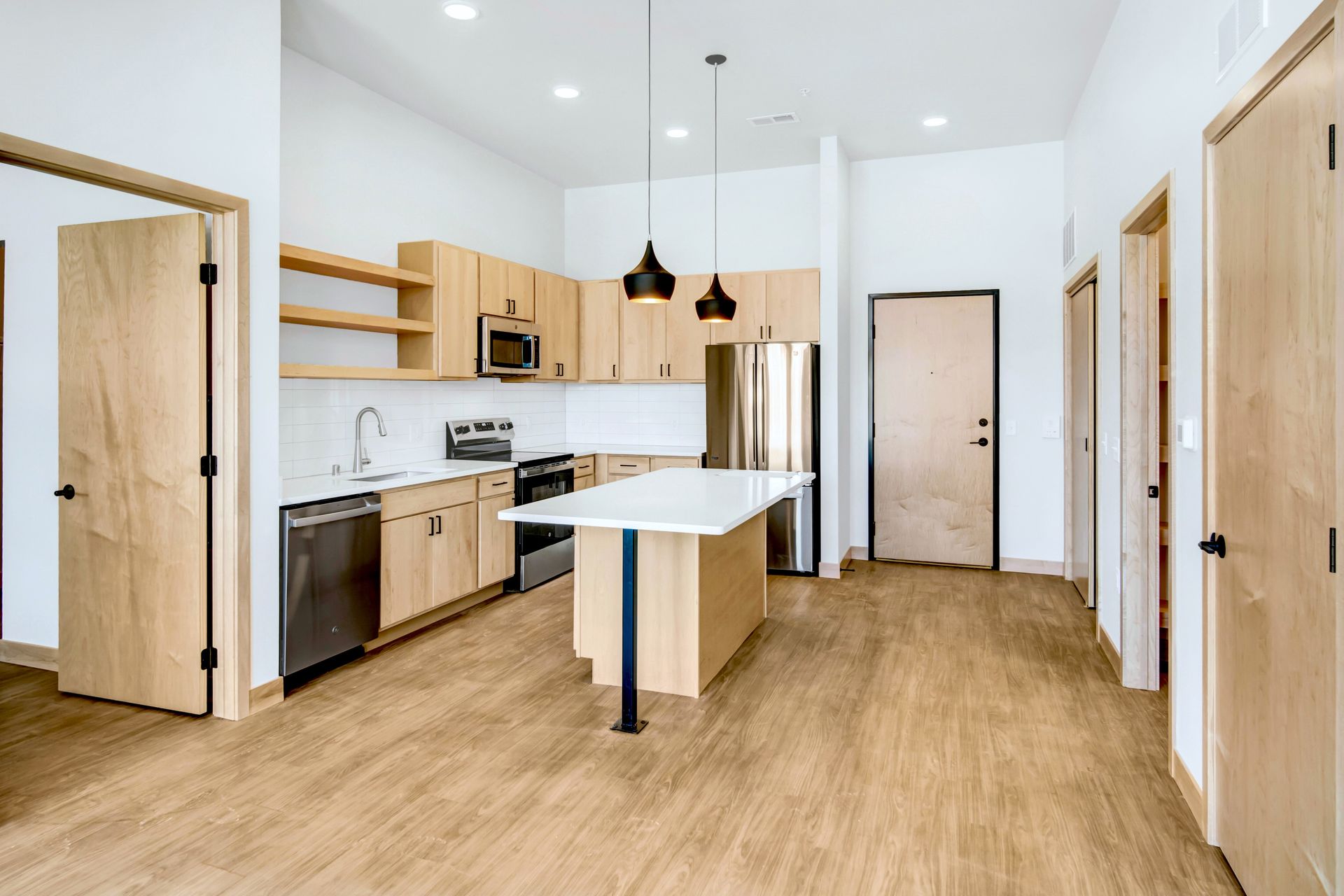A kitchen with wooden cabinets , stainless steel appliances , and a large island.