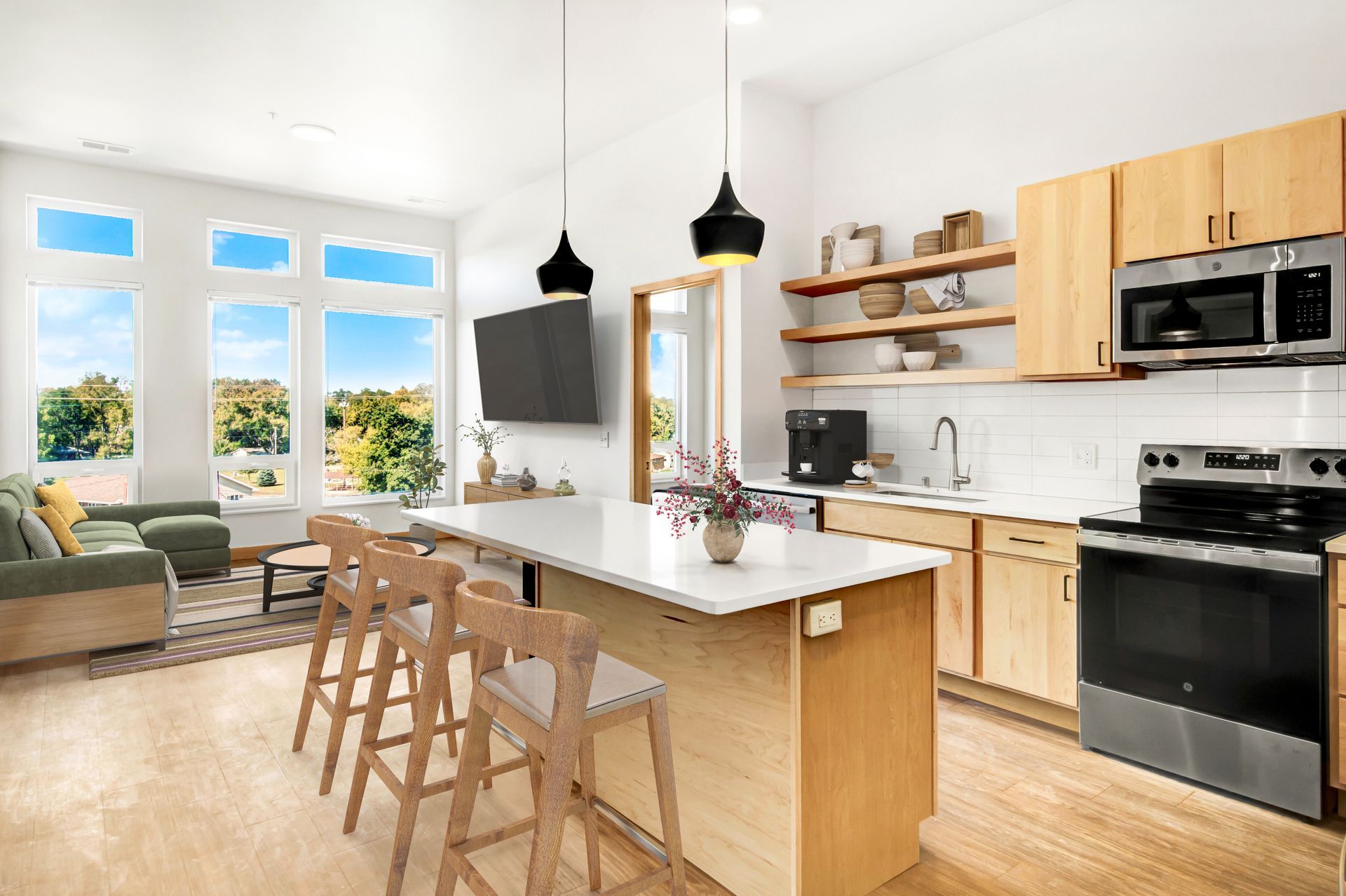 A kitchen with wooden cabinets , stainless steel appliances , a large island and a flat screen tv.