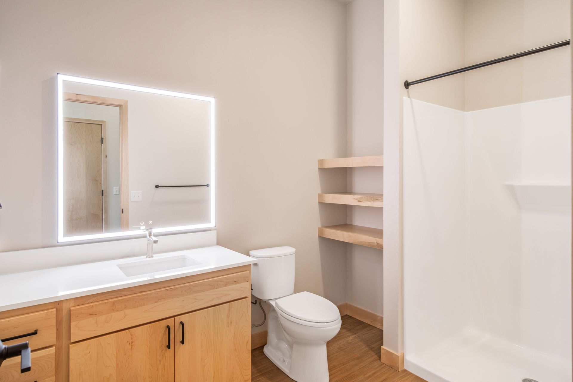A bathroom with a toilet , sink , mirror and shower.