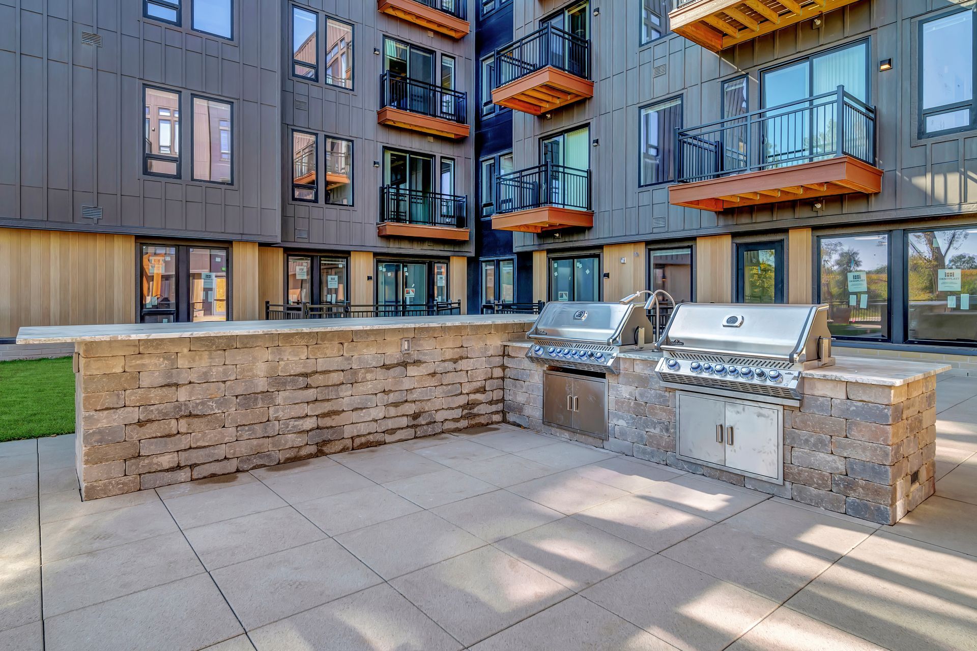 A grill is sitting on a patio in front of a building.