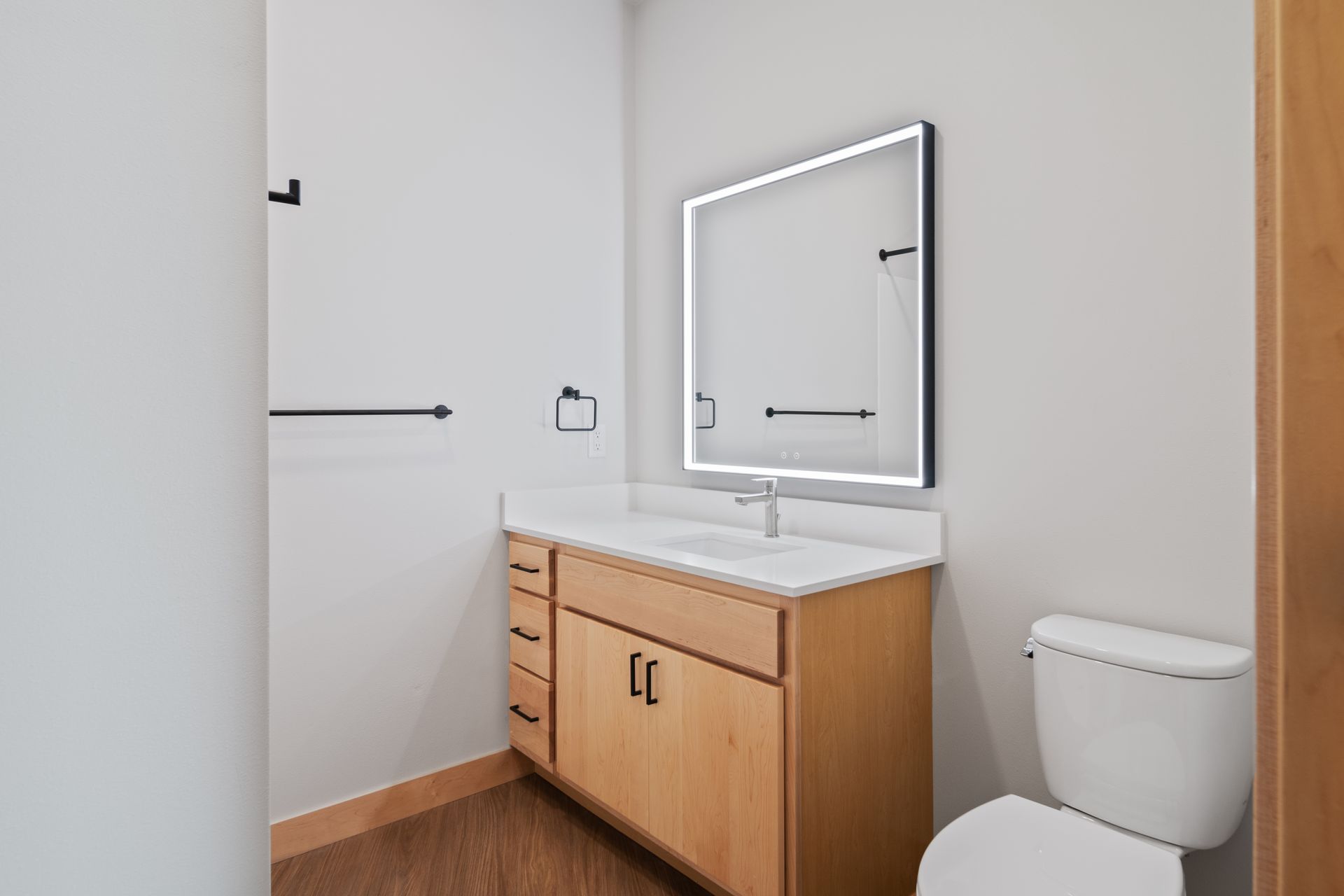 A bathroom with a sink , toilet and led mirror.
