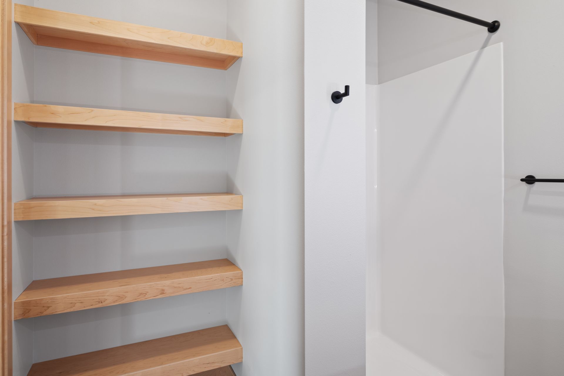 A bathroom with wooden shelves and a shower stall.