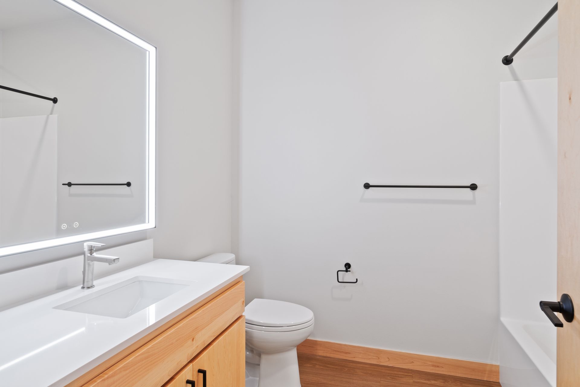 A bathroom with a toilet , sink , led mirror and shower.