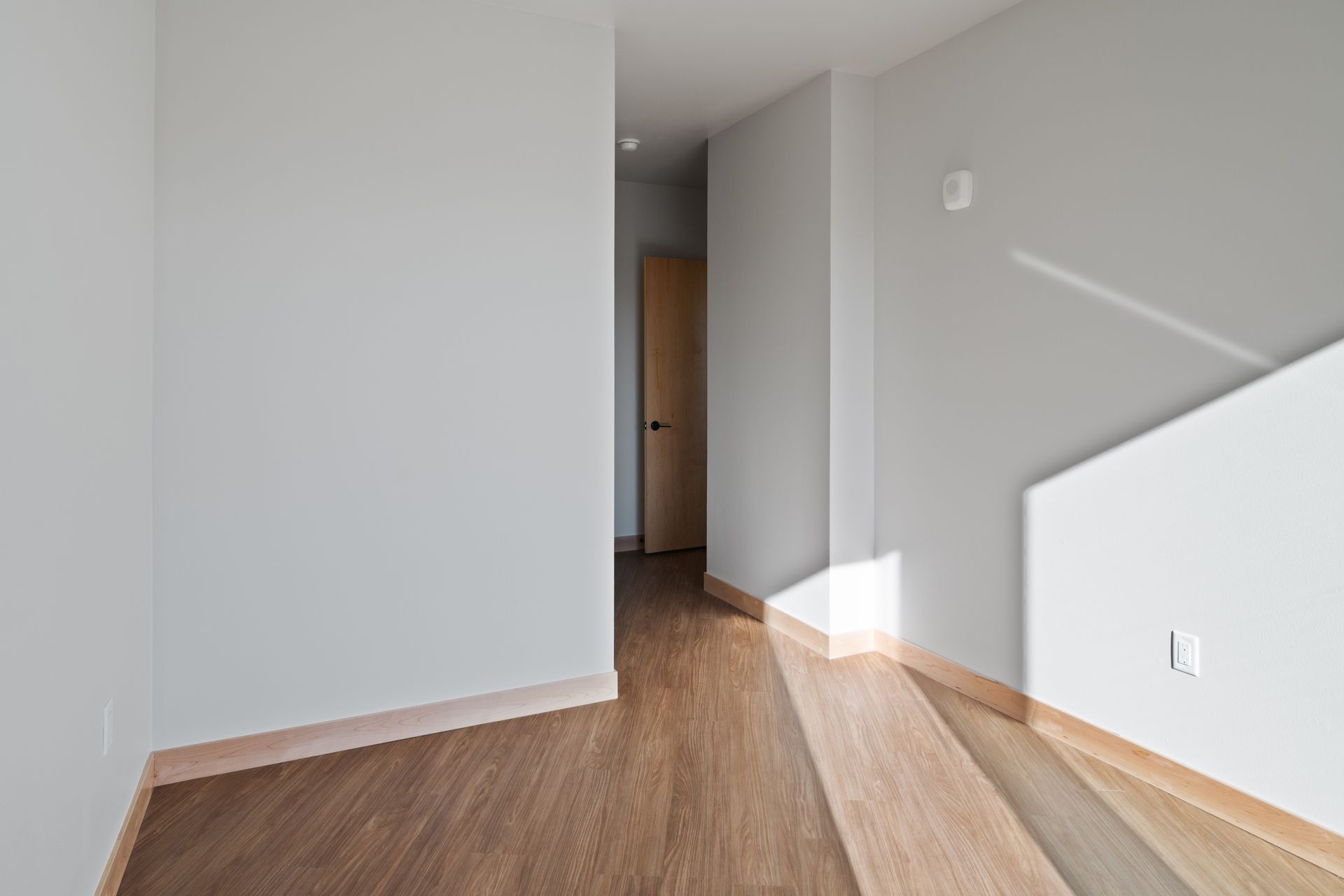 An empty bedroom with lvp floors and white walls.