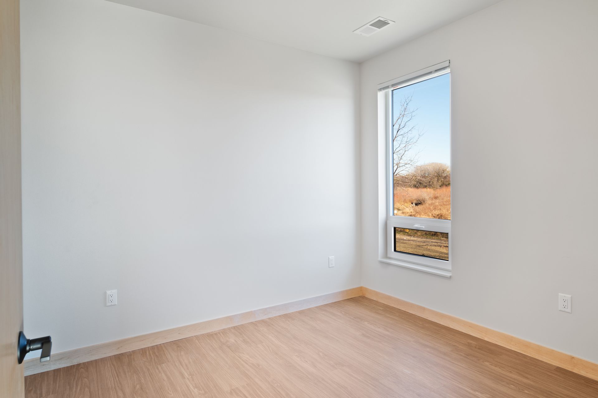 An empty room with a window and a lvp floor.