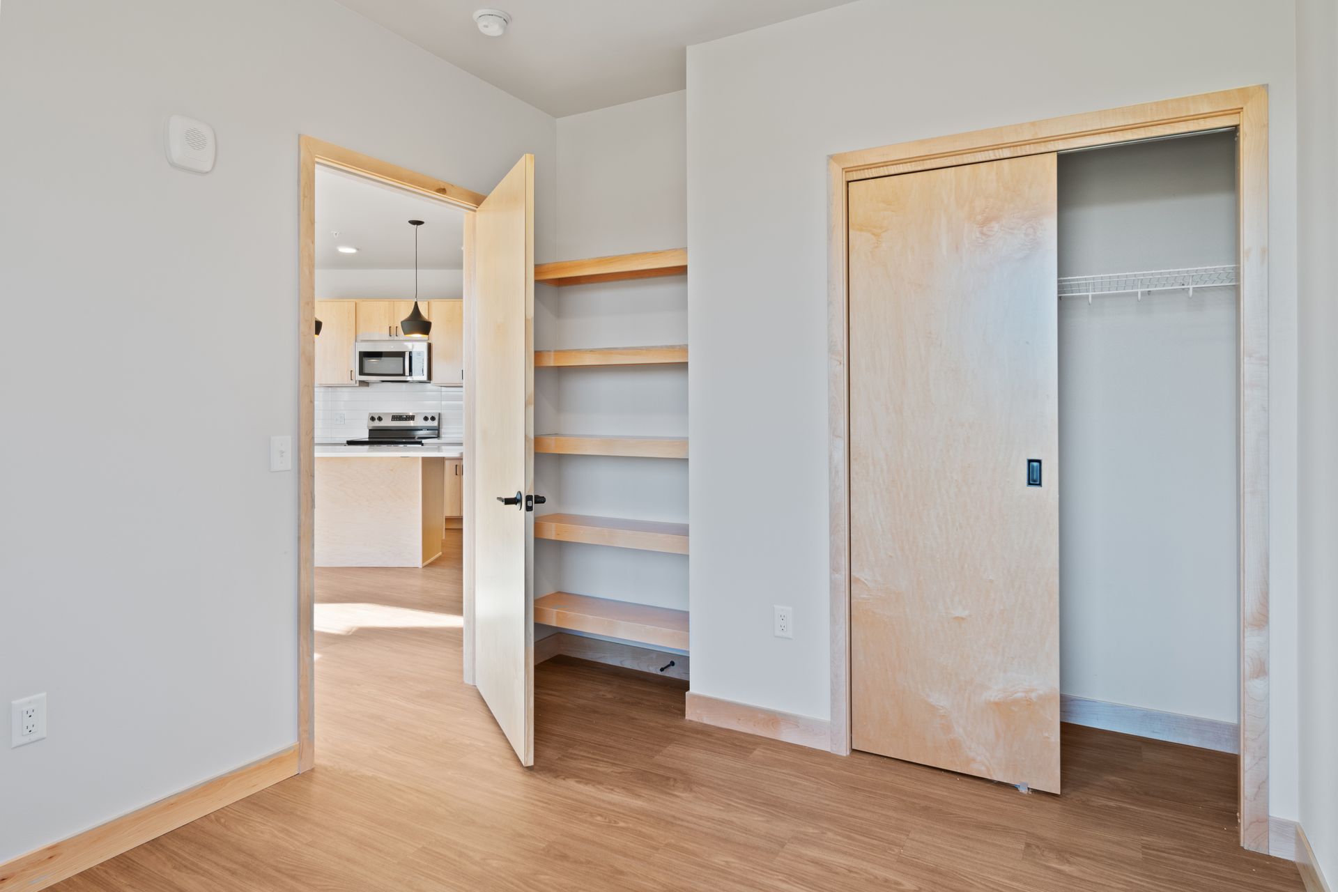 An empty room with a closet and shelves in it.