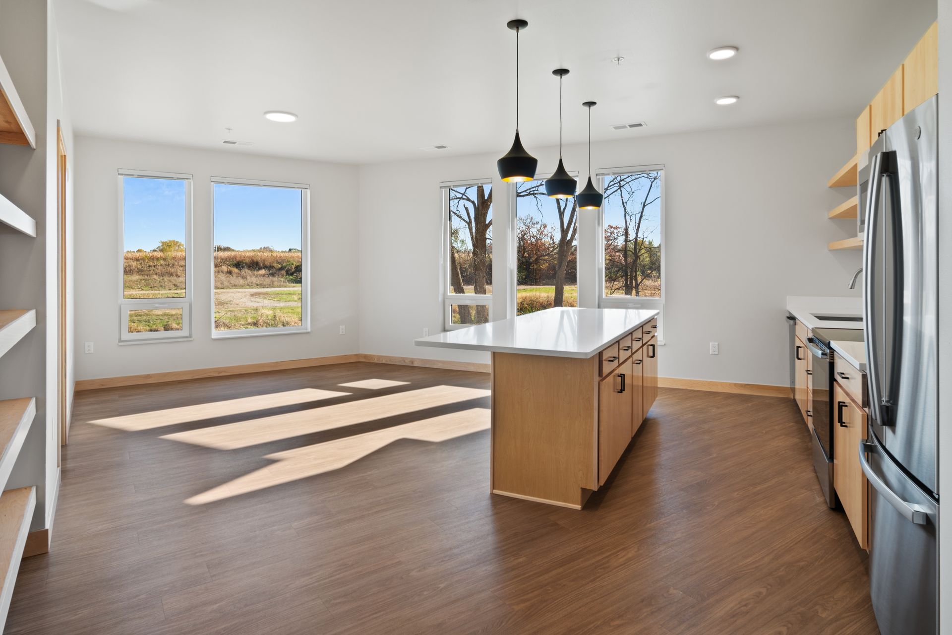 Living room with lots of windows and large island in the middle of the kitchen.
