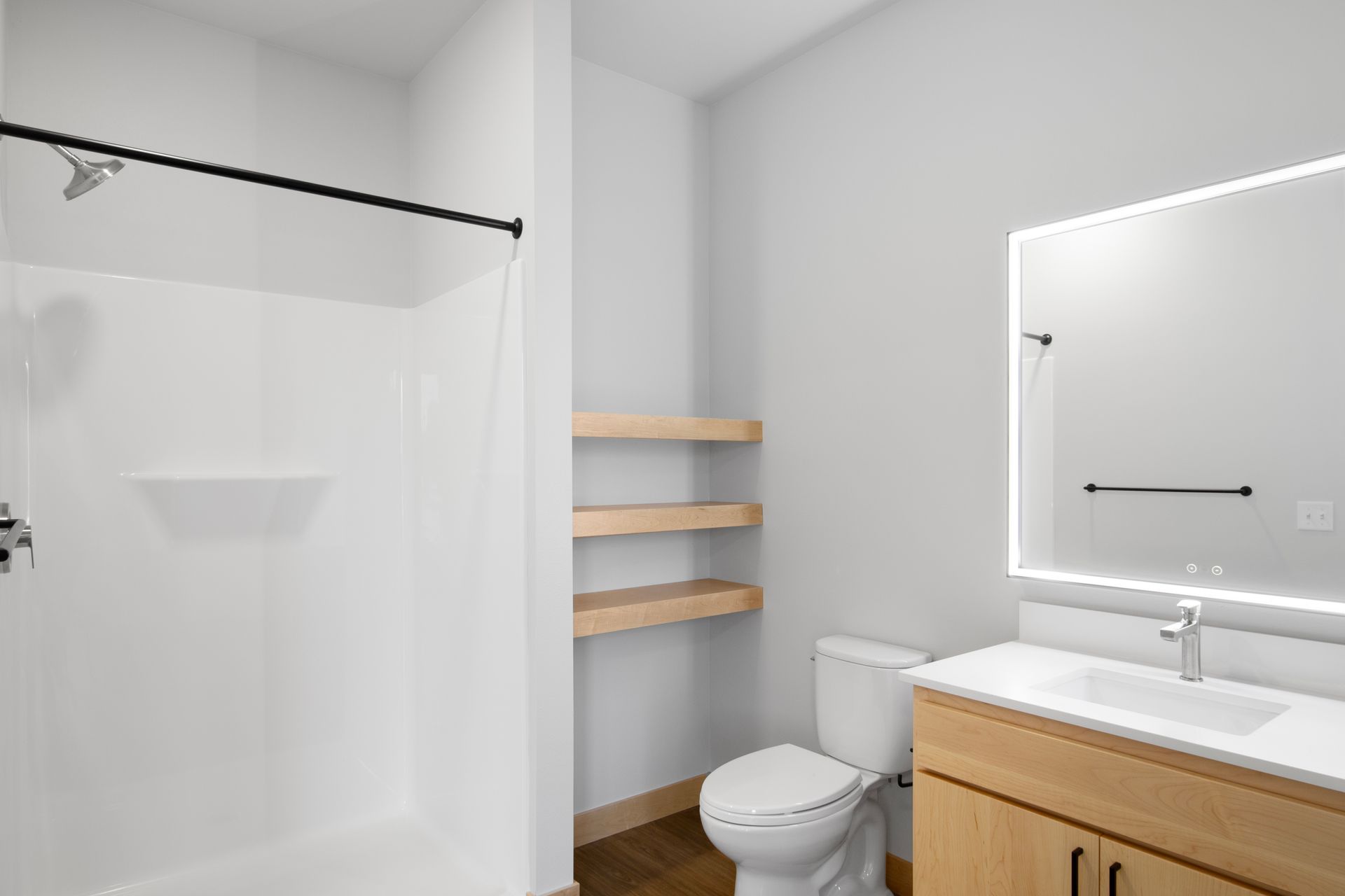 A bathroom with a toilet , sink , shower and led mirror.