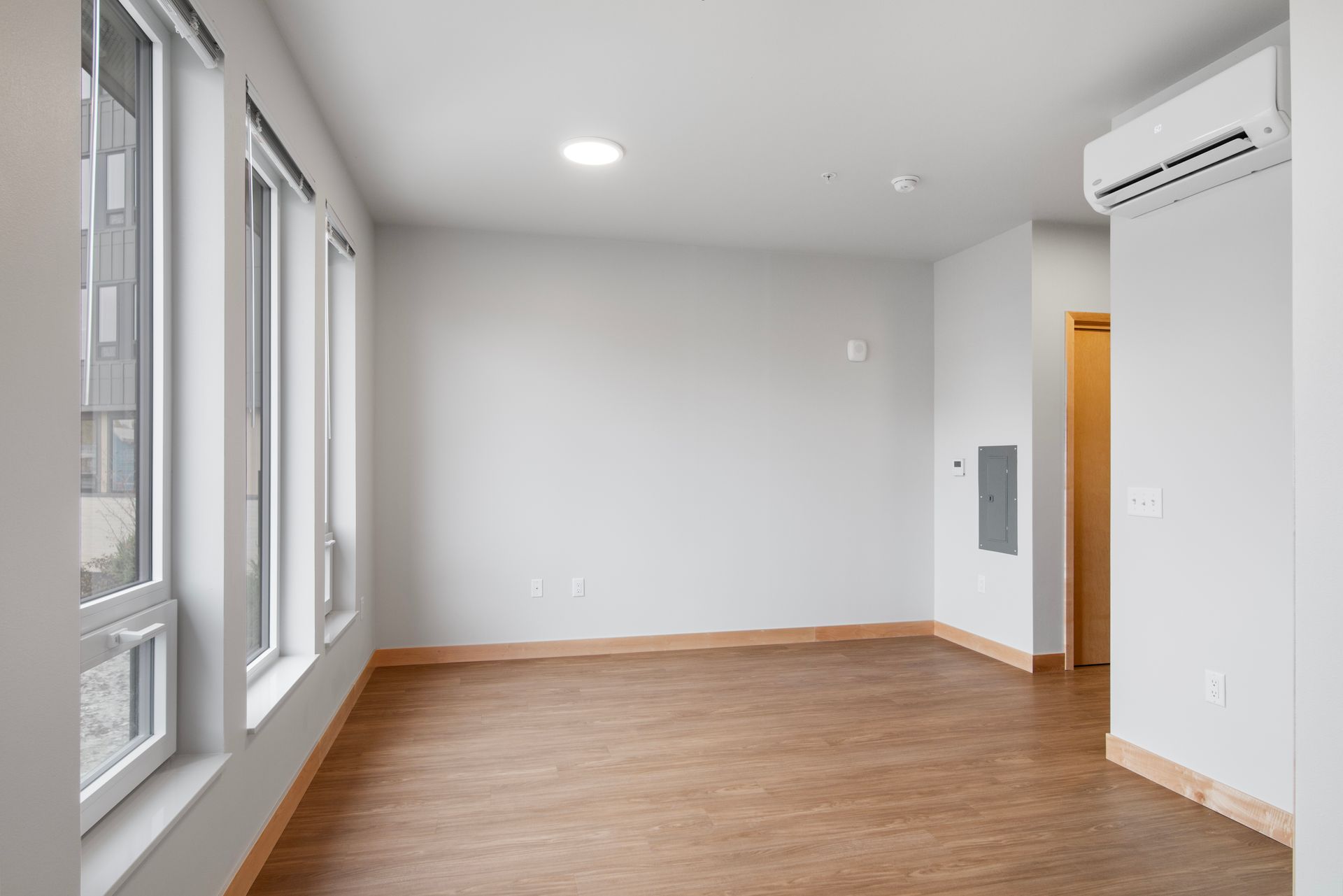 An empty living room with hardwood floors and white walls.