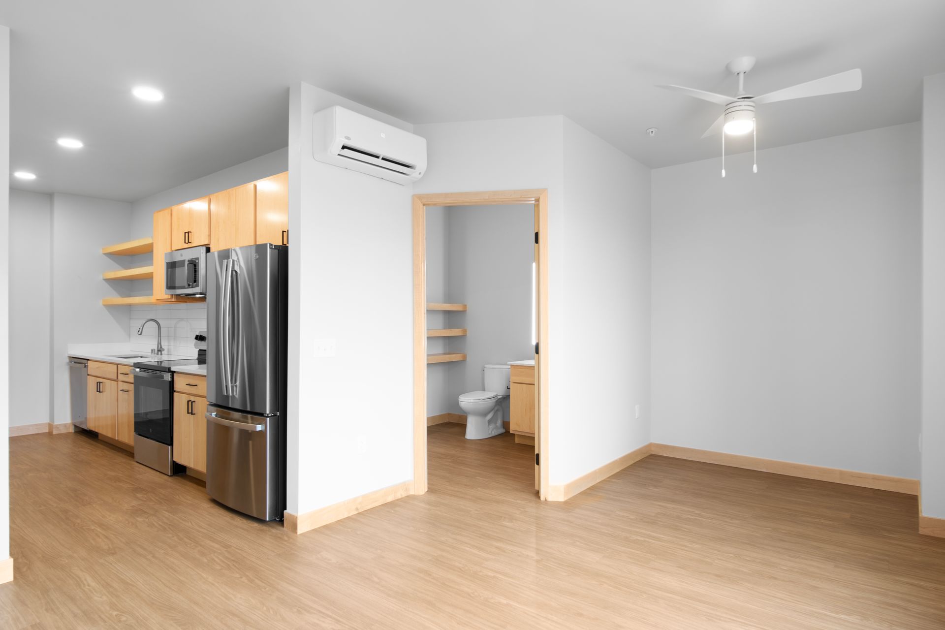 An empty apartment with a kitchen , living room , and bathroom.