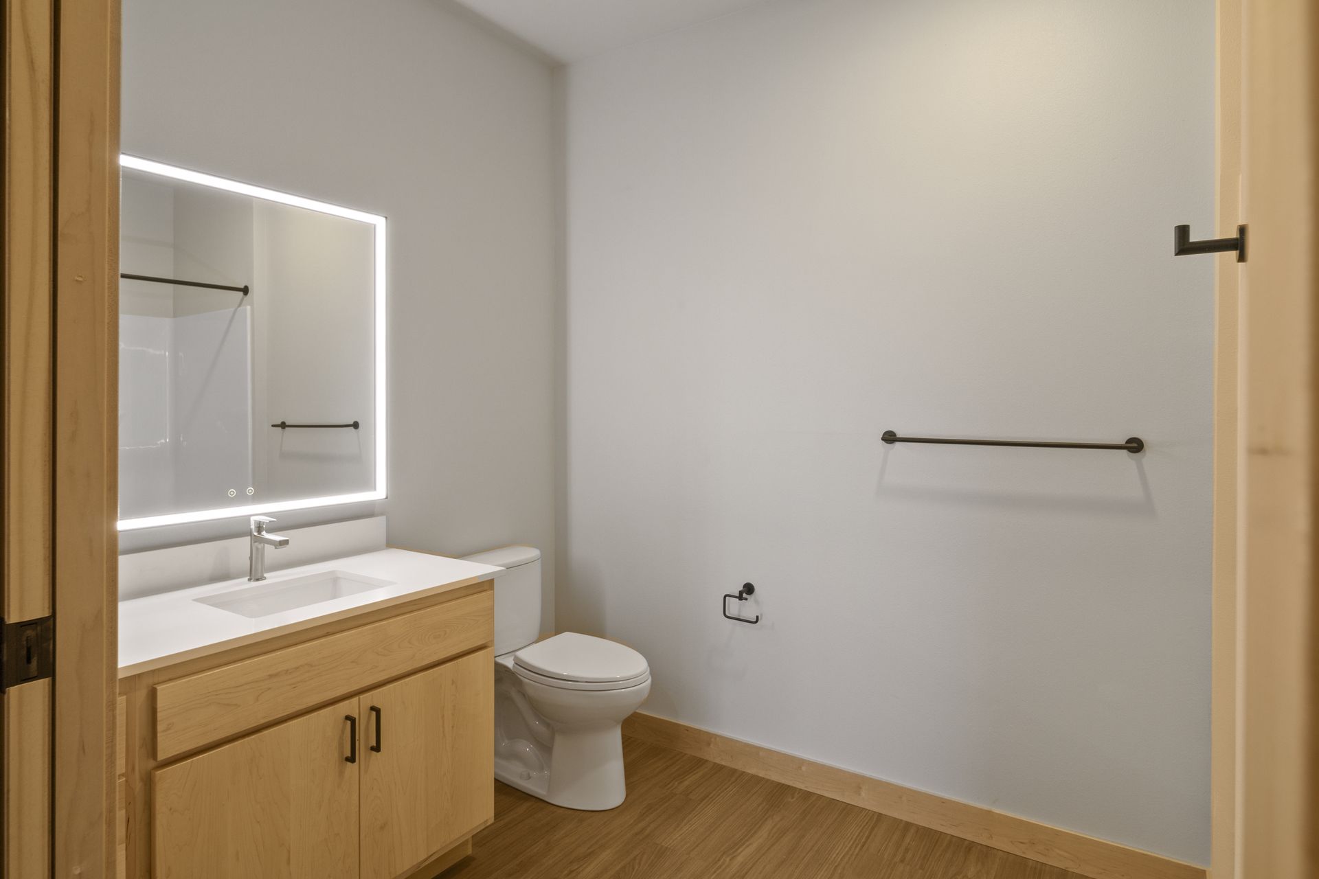 A bathroom with a toilet , sink and led mirror.