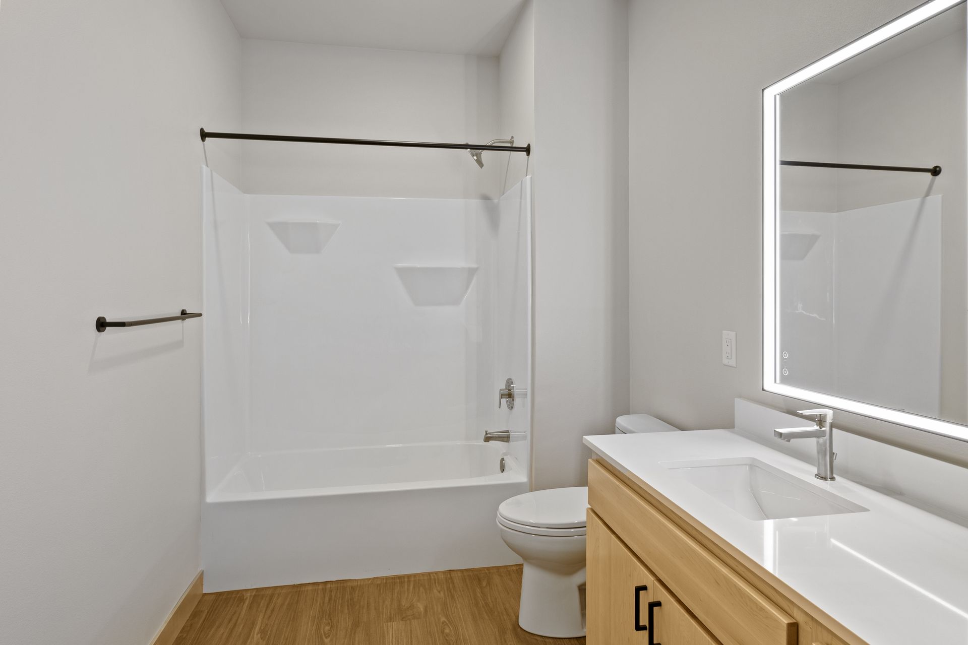 A bathroom with a sink , toilet , bathtub and led mirror.