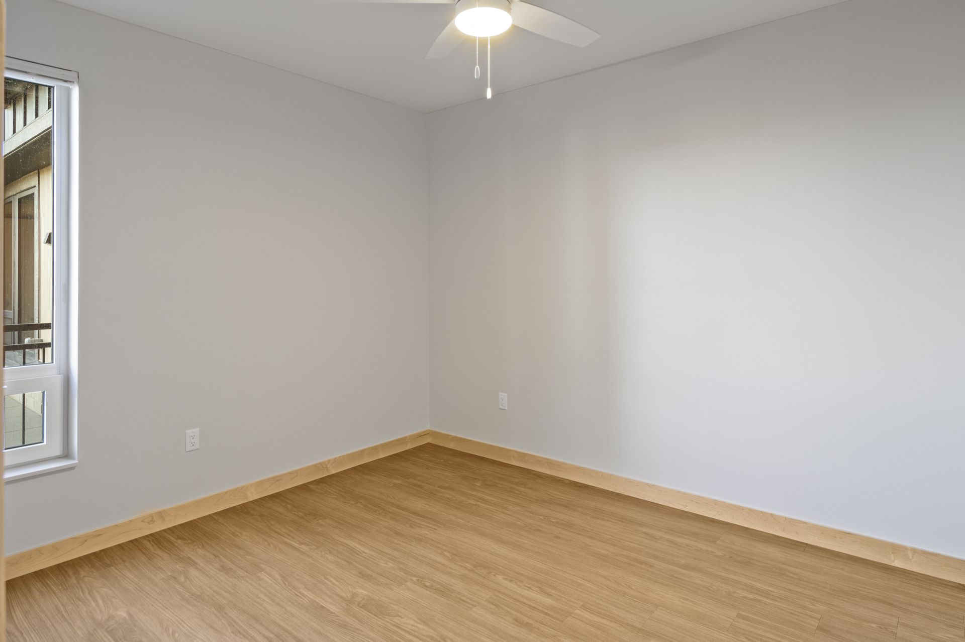 An empty bedroom with lvp floors and a ceiling fan.