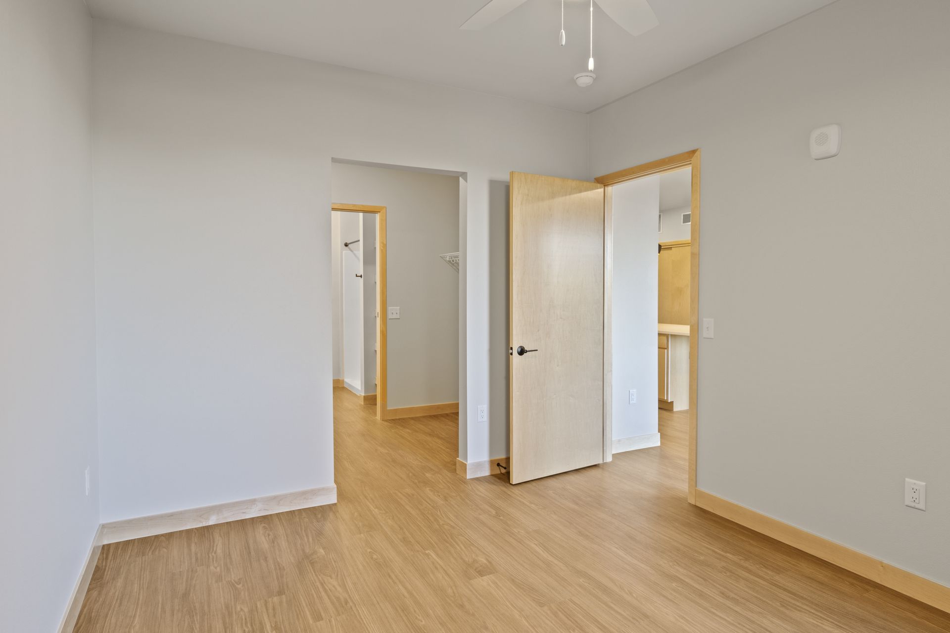 An empty room with lvp floors and a ceiling fan.