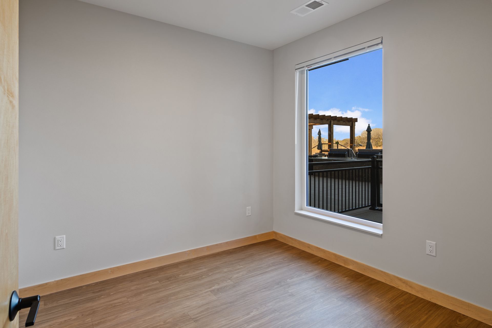 An empty room with a large window and a lvp floor.
