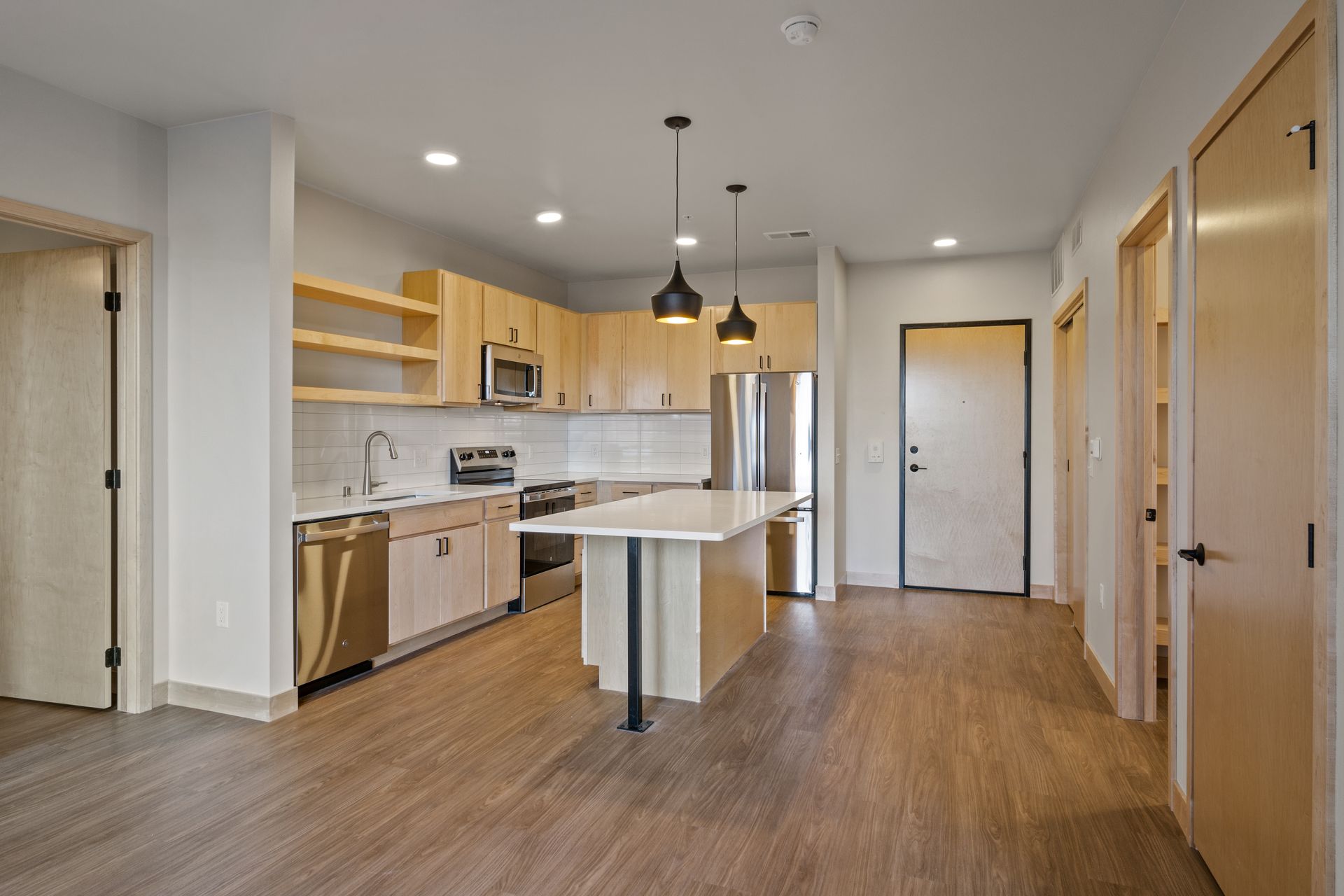 A kitchen with wooden cabinets , stainless steel appliances , and a large island.