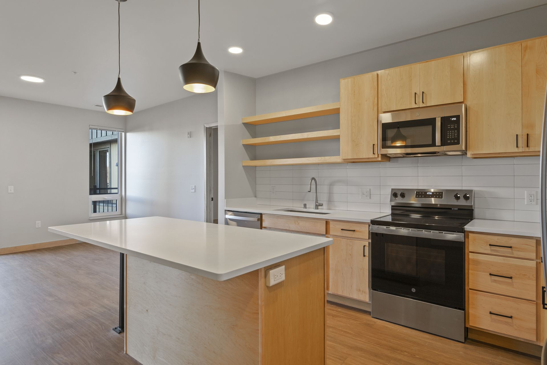 A kitchen with wooden cabinets , stainless steel appliances , and a large island.
