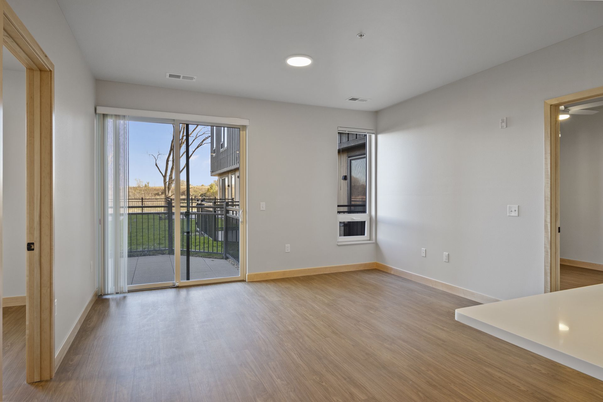 An empty living room with a sliding glass door and a patio.