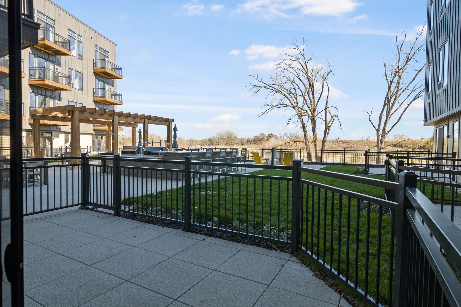 A patio with a fence and a view of community terrace.