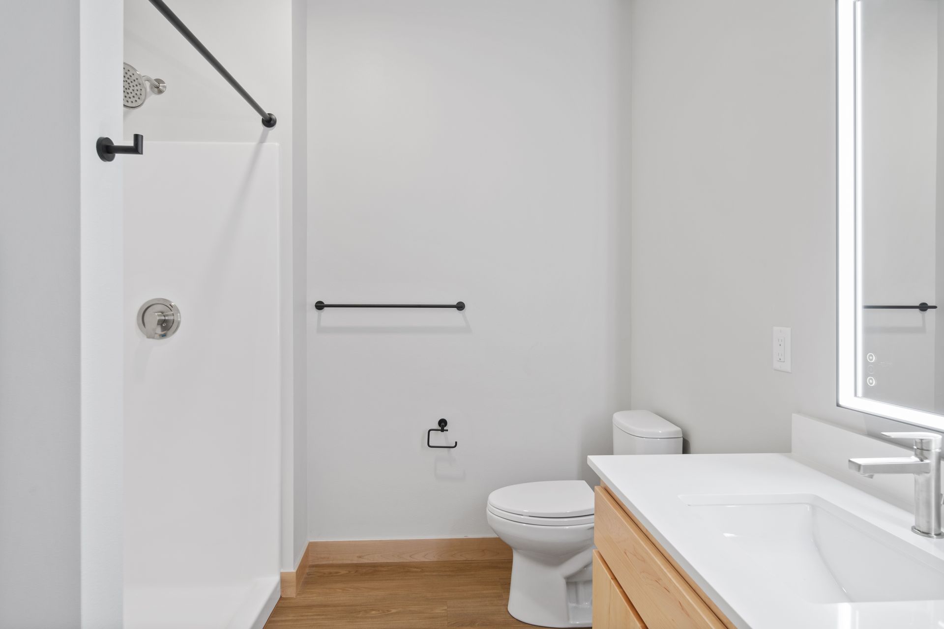 A bathroom with a toilet , sink , shower and led mirror.