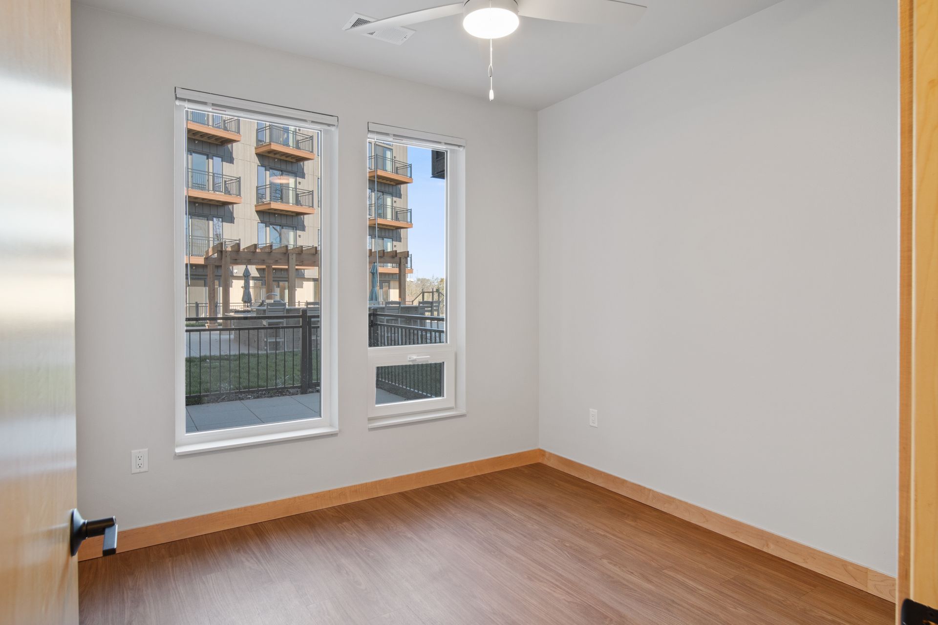 Spacious bedroom with two windows and a ceiling fan.