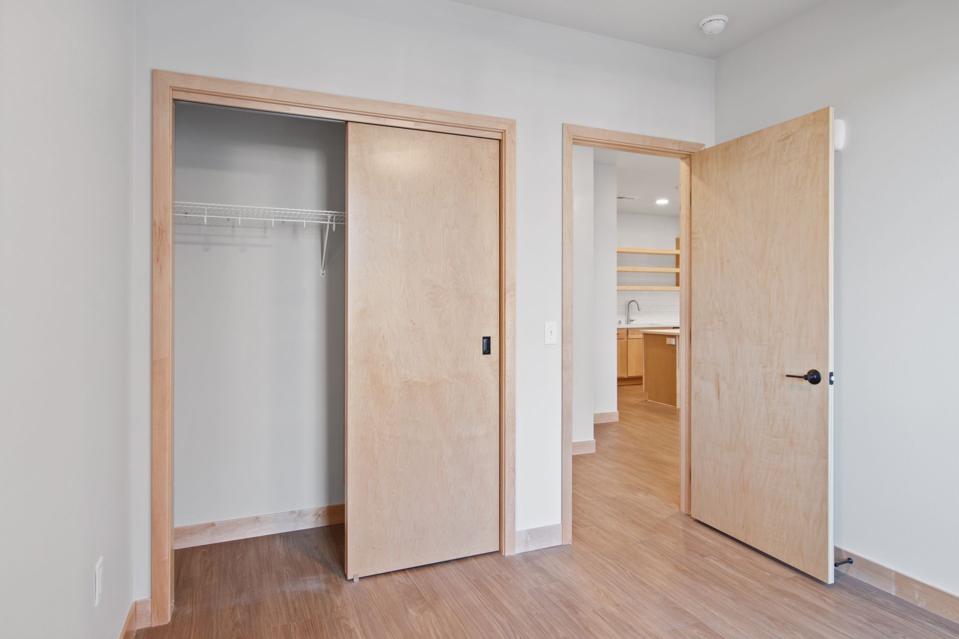 Spacious bedroom with two wooden doors and a closet.