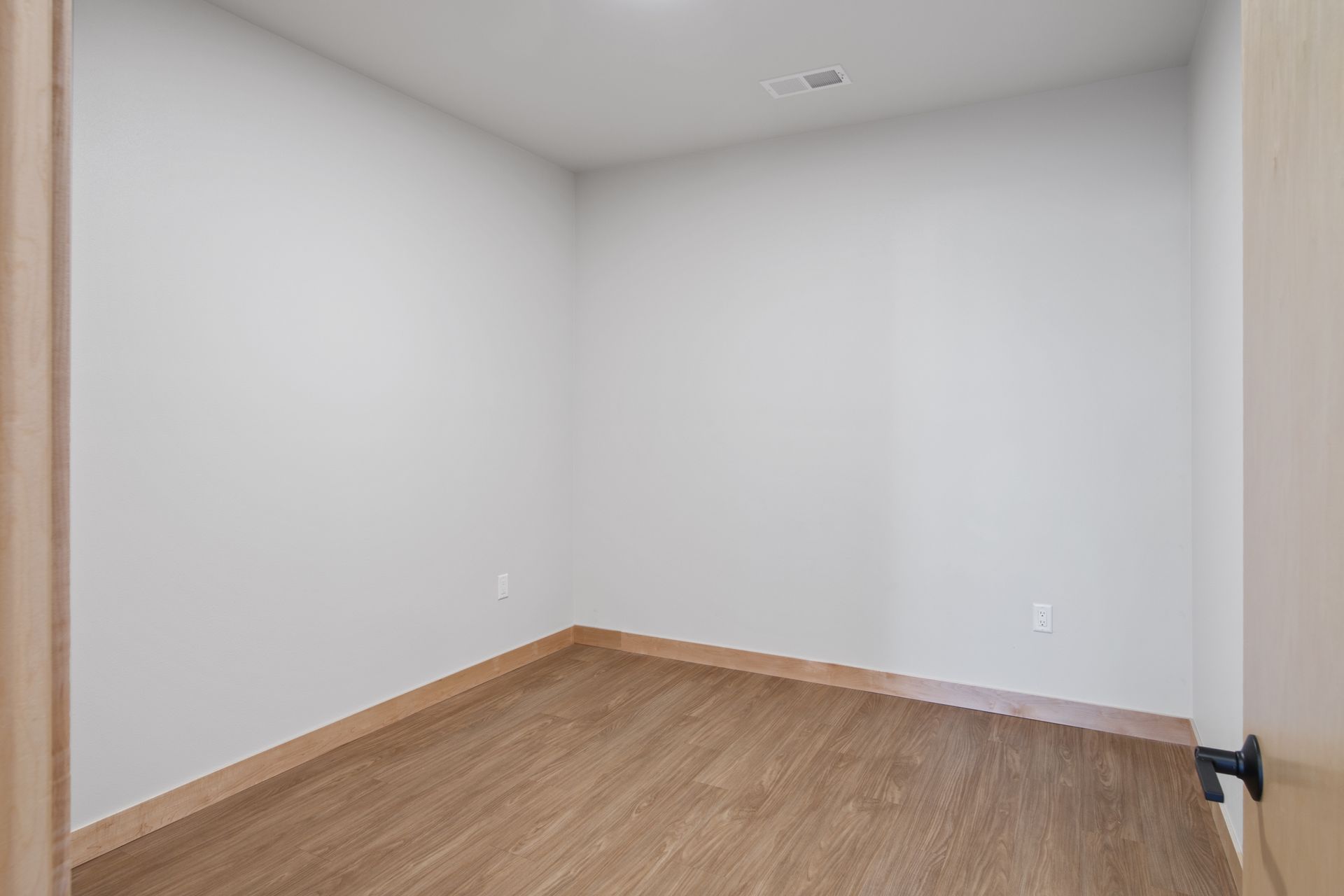 Spacious bedroom with lvp flooring and white walls.