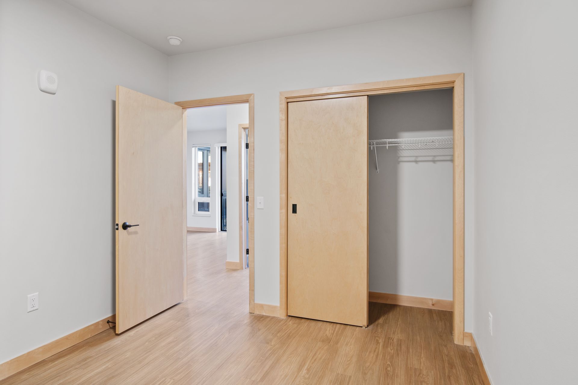 Spacious bedroom with two wooden doors and a closet.