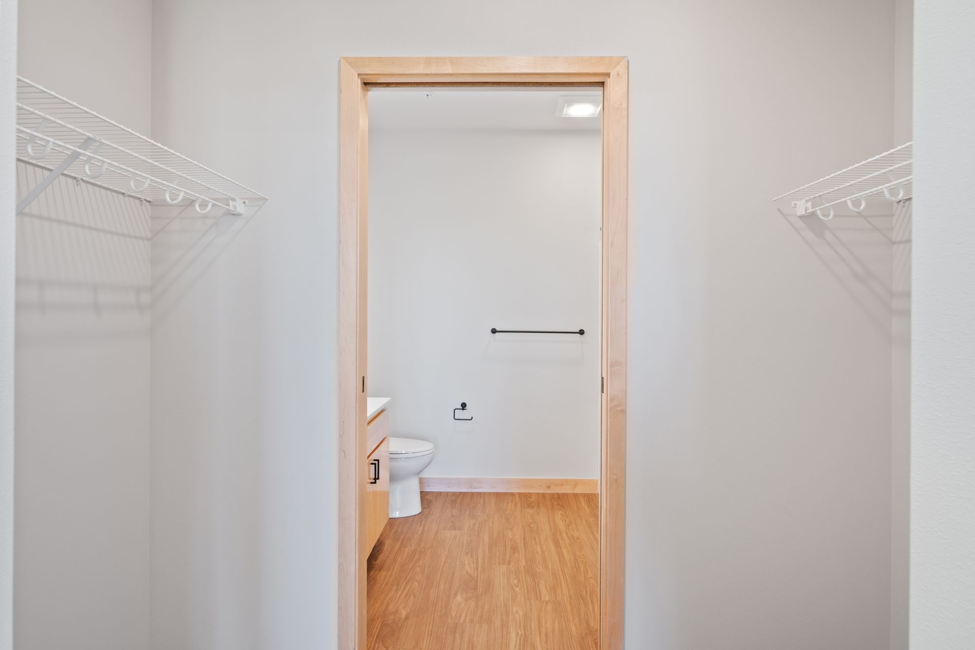 A walk-in closet with a toilet , sink , and clothes racks.