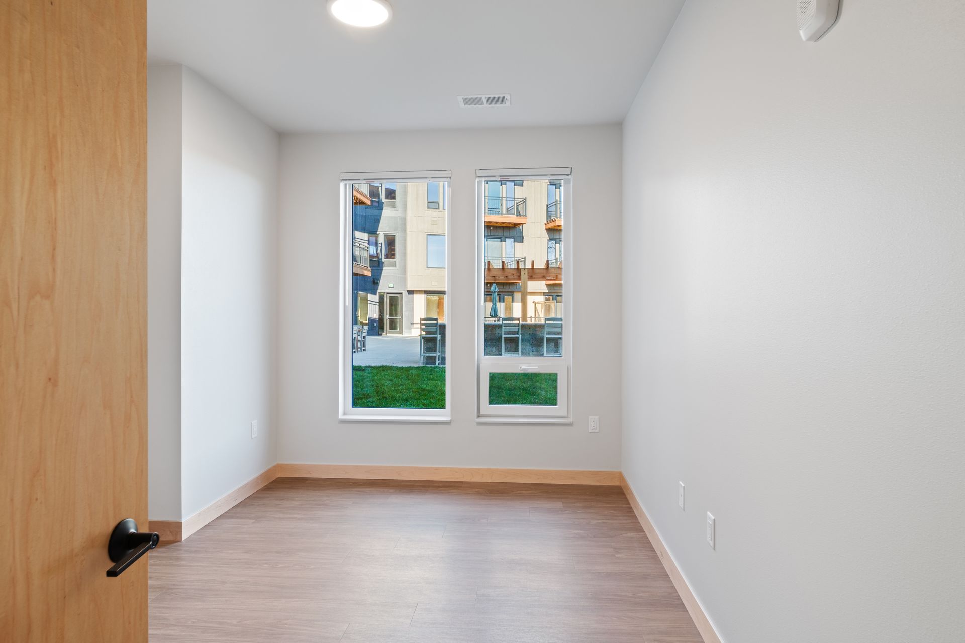 An empty bedroom with two windows and a lvp floor.